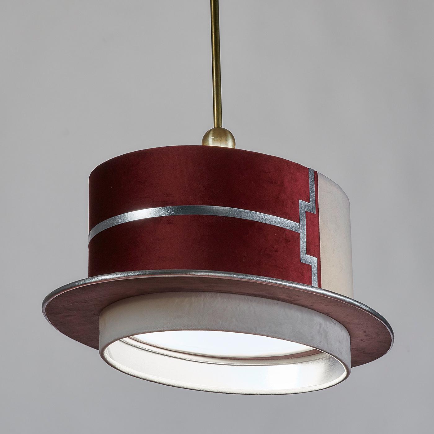 The shape of this pendant lamp is inspired by the hats of the Venetian gondoliers. Handcrafted entirely of ivory and magenta velvet with ivory and silver leather trims, this elegant pendant light features a geometric decoration in silver laminate.