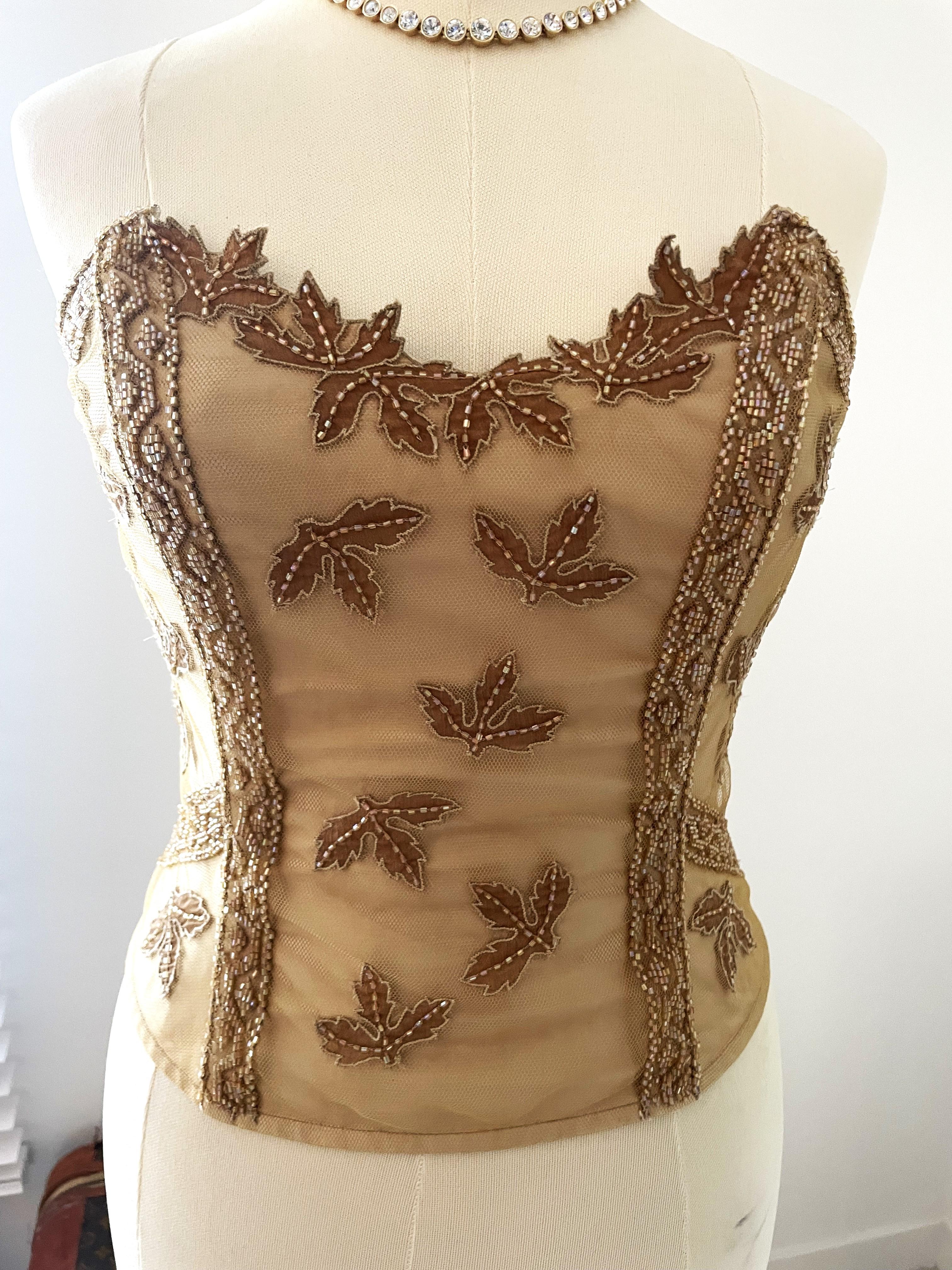 RITMO DI PERLA LA PERLA 

Vintage 2000s very well kept (new) gold luxury and high-quality corset top. Very sensual & sexy. Embroidered with a layer of tulle with leaves and beads and a zipper at the back.

Vintage La Perla corsets typically feature