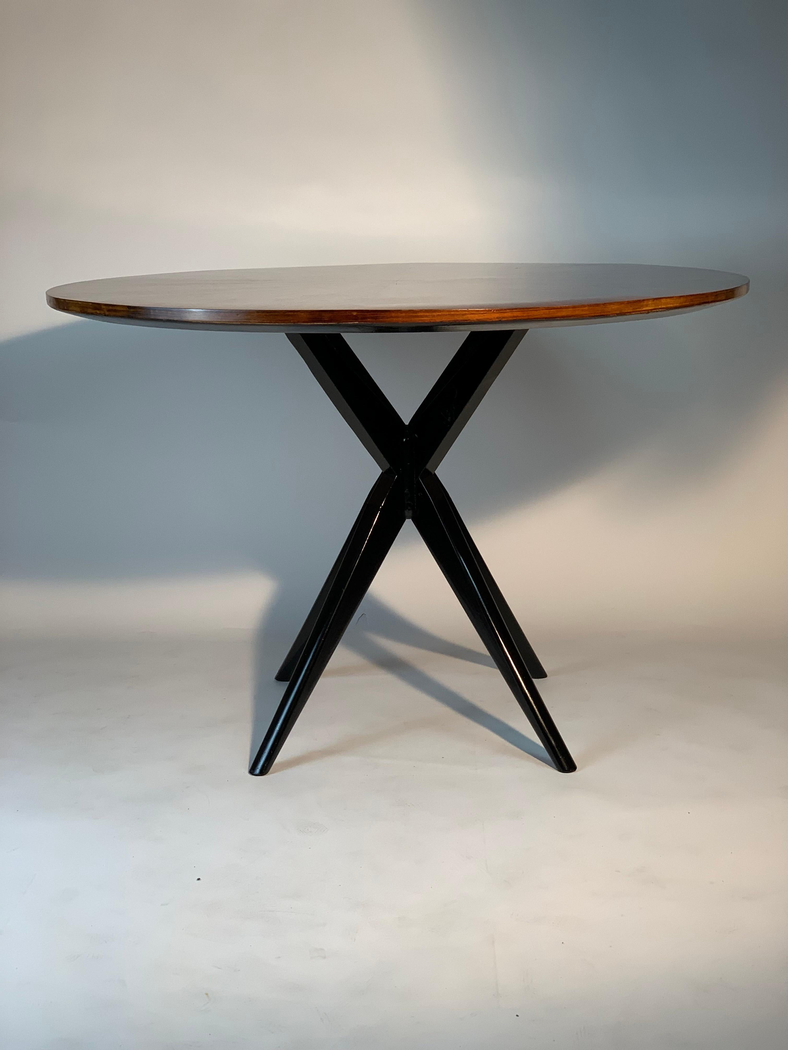 Italian Mid century round table made by the Permanent Furniture Exhibition Cantù - Milan the black lacquered solid wood base is a simple and stylized intersection that makes this round table modern and contemporary, it supports a top inlaid with
