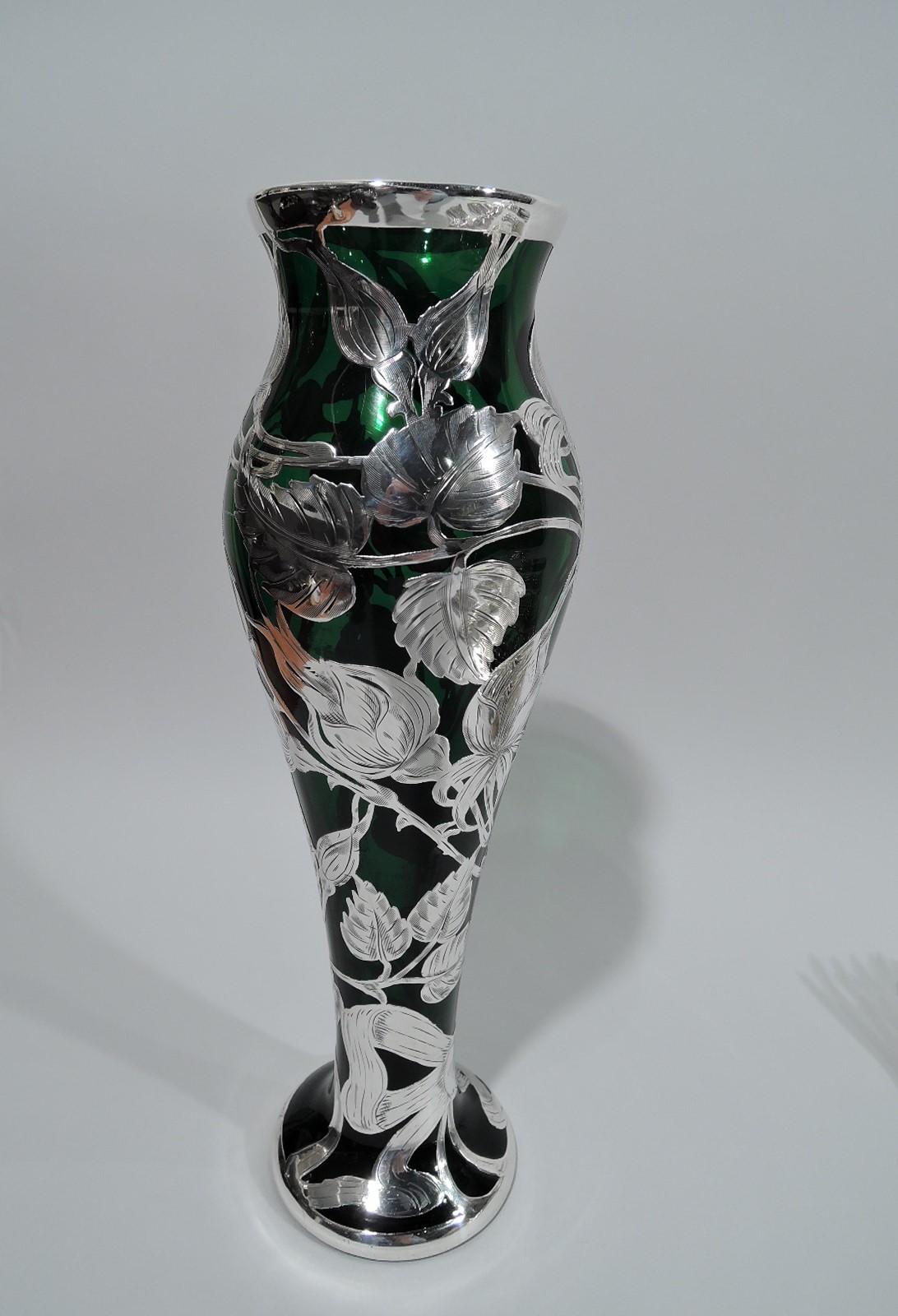 Turn-of-the-century Art Nouveau glass vase with engraved silver overlay. Ovoid body flowing into spread foot. Overlay in form of rose branch with buds and blooms on floaty, leafing tendrils. Ribbon cartouche engraved with interlaced 3-letter