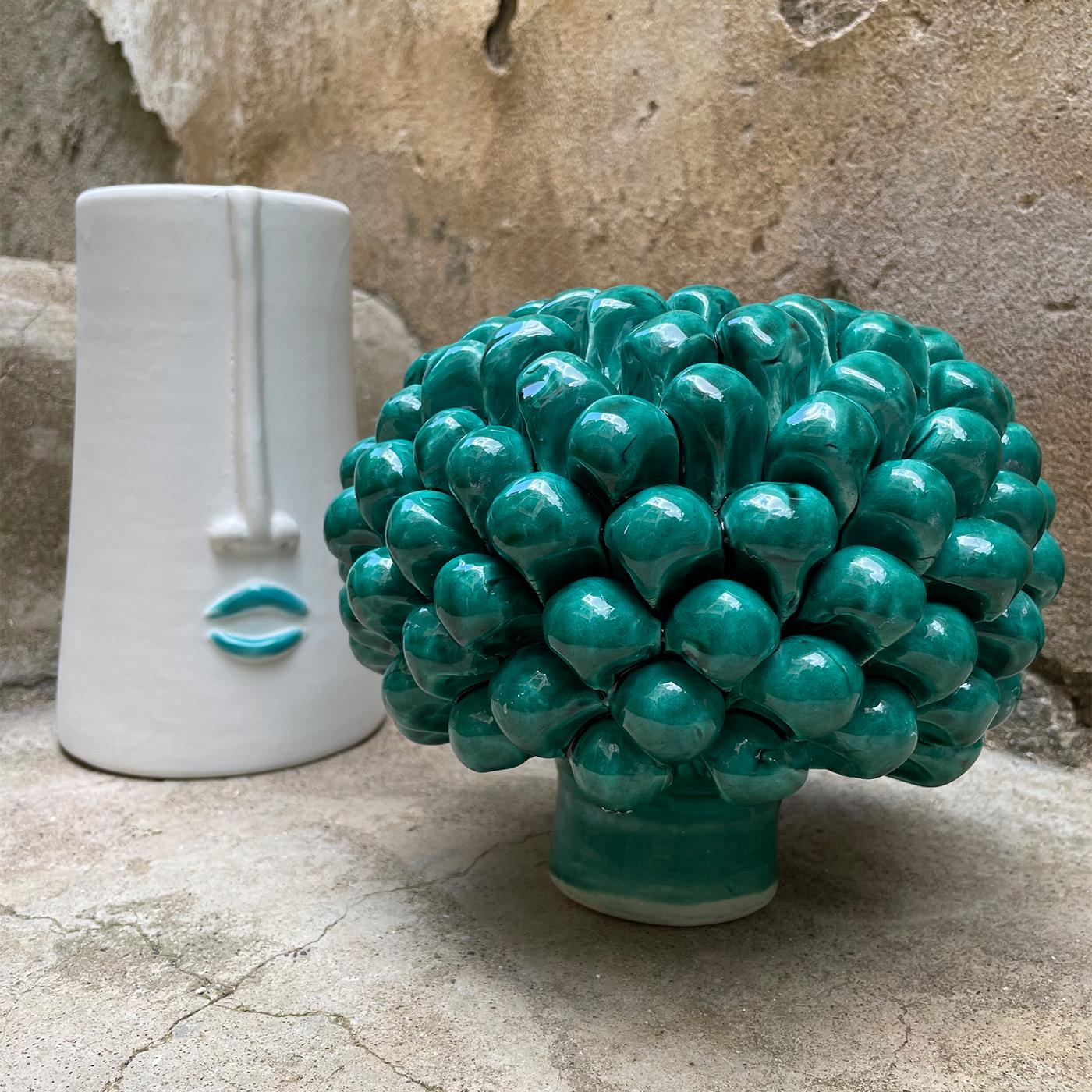 Superb as a centerpiece for an entryway console, this precious ceramic piece brims with romantic and sculptural charm. Anthropomorphic traits accent the central body, which comes topped by a stunning lid in the shape of a vivid green pine cone.