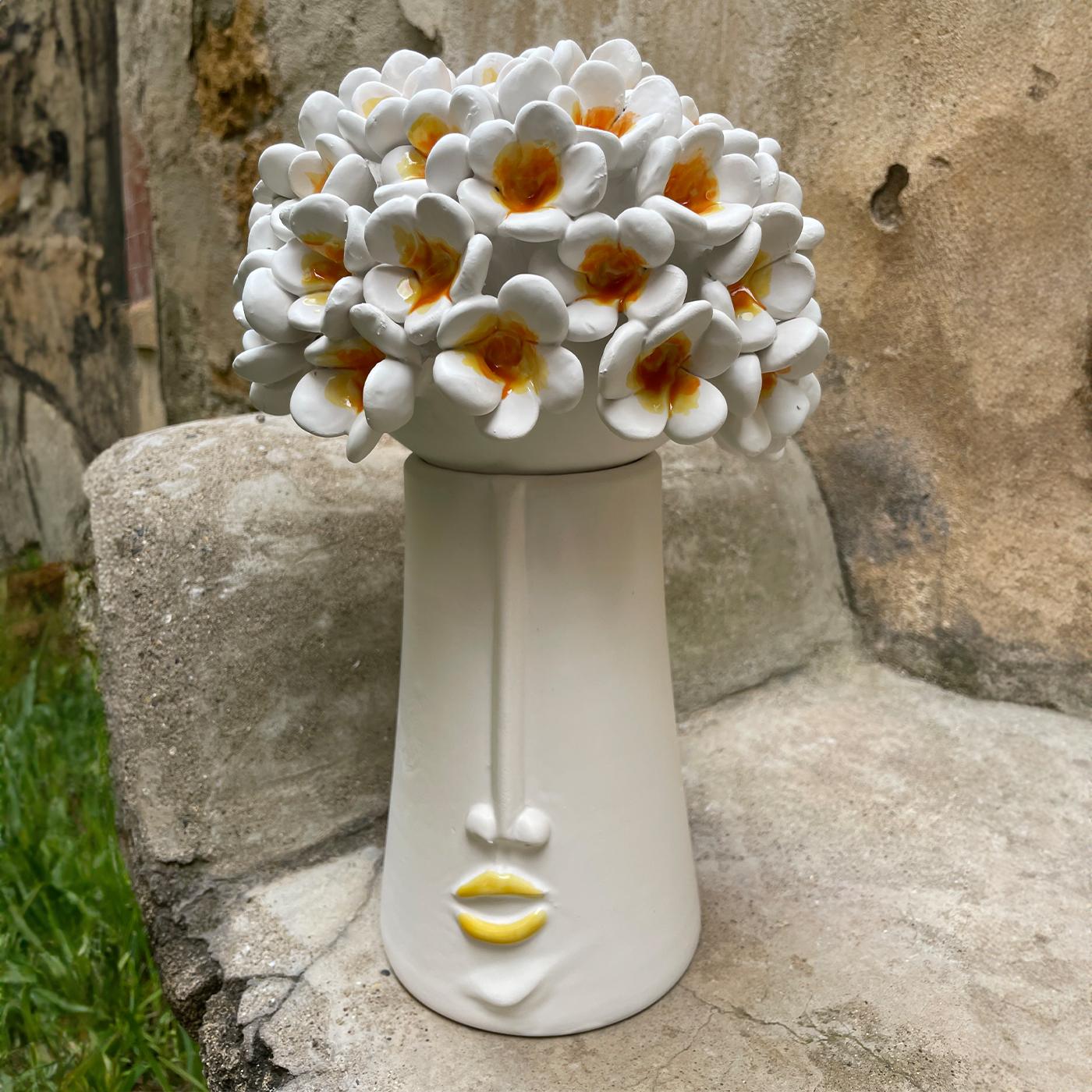 A bouquet of white flowers with fleshy petals is the lid to this precious ceramic piece flaunting elegant anthropomorphic traits. An ideal addition to a contemporary dining table or entryway console, the design incorporates a wide inner storage unit