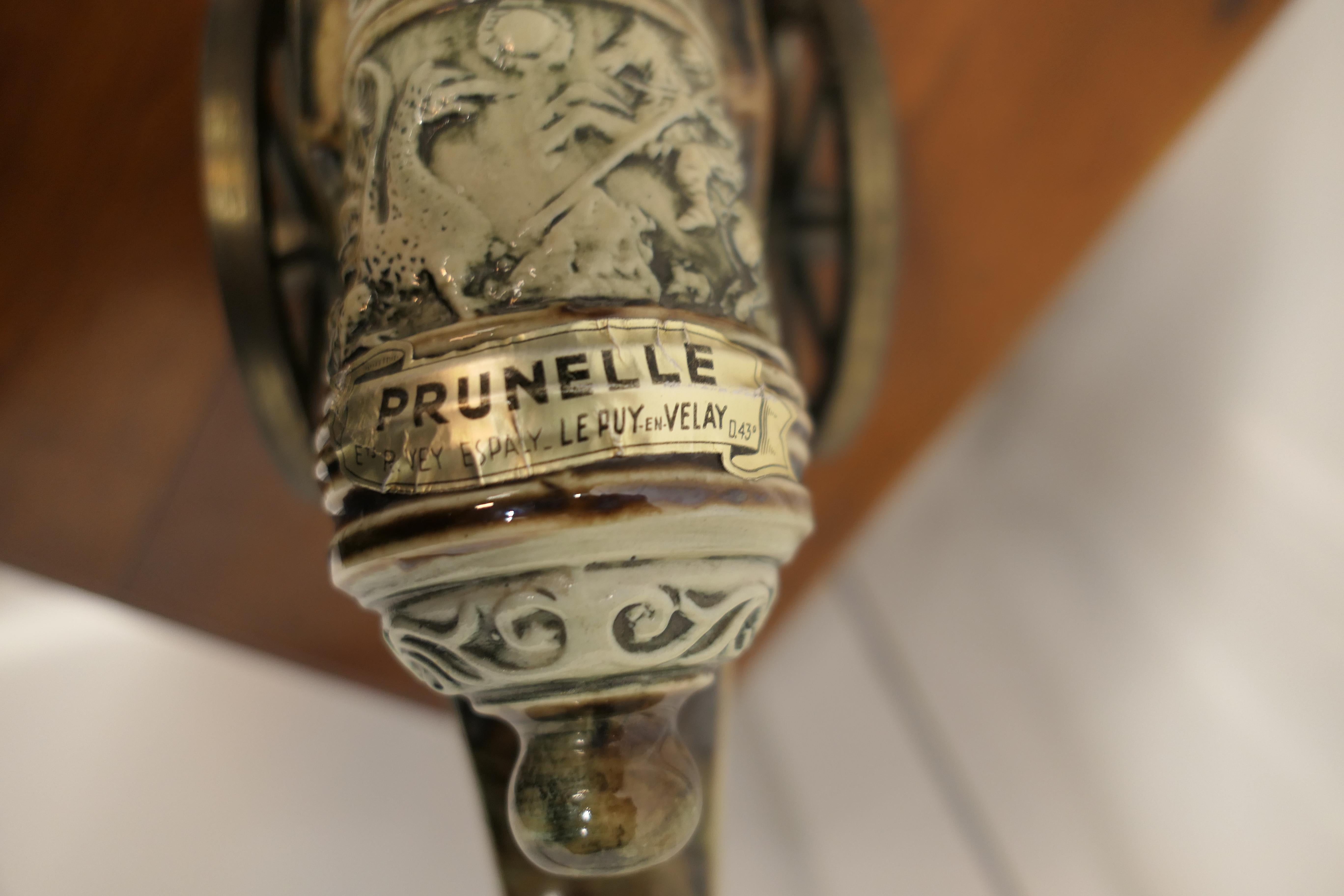 La Prunelle du Velay Steingutkanone Likörflasche 

Eine charmante Likörkutsche aus Steingut, eine dekorative napoleonische Kanone auf einer Metallkutsche mit Rädern, die über den Tisch rollt und beim Kippen Ihren Likör ausschenkt. 
Dieser ist