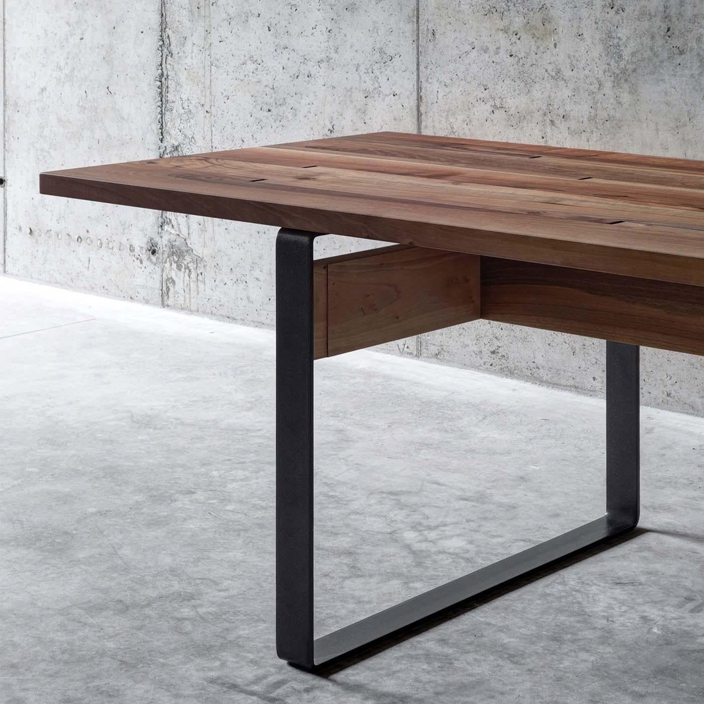 Designed by Act_Romegialli, this stunning dining table combines the warmth of walnut and the cool elegance of steel. The top showcases the unique grain of the wood and comprises five boards that were asymmetrically cut and assembled with an