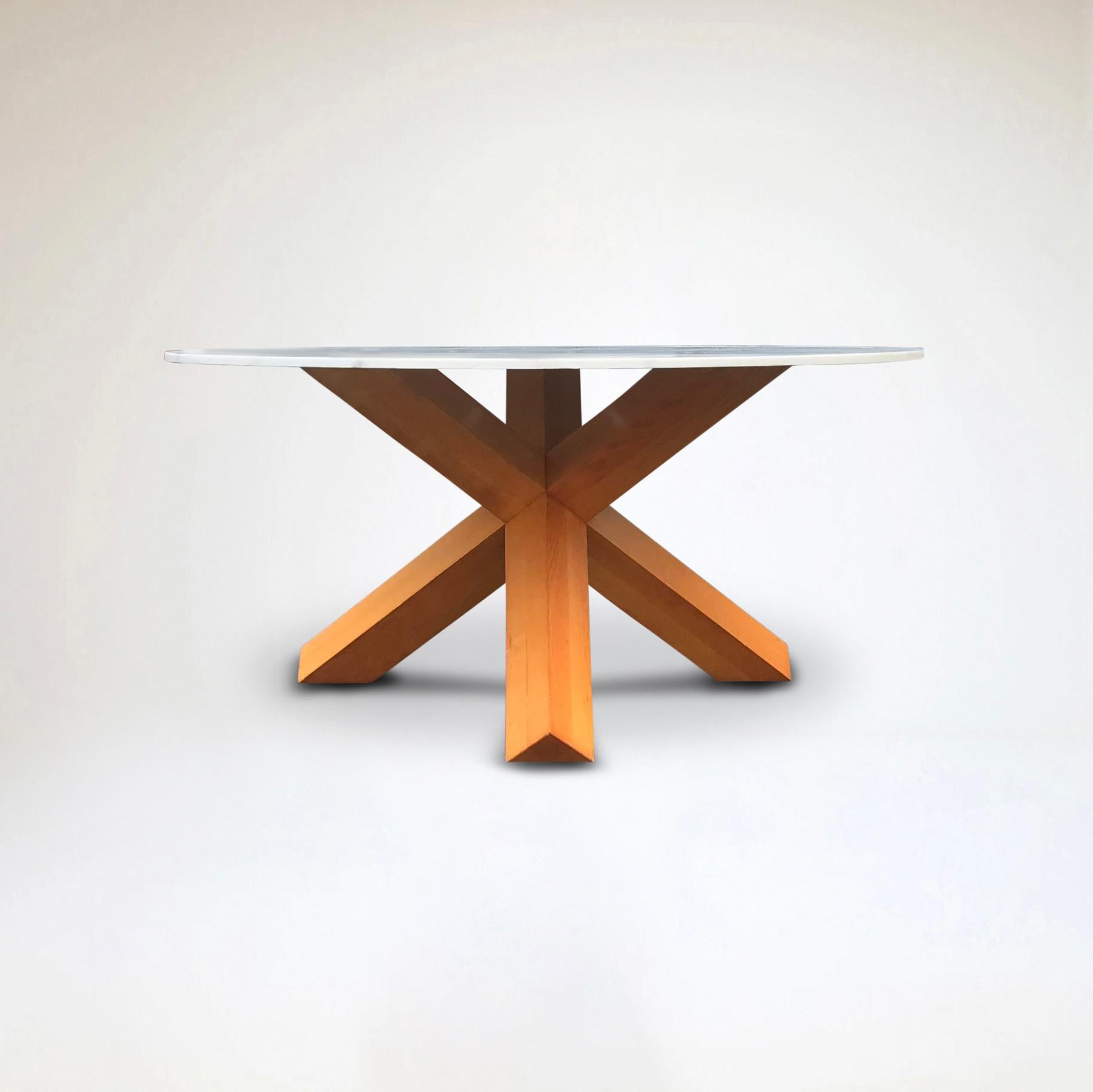 Der 1976 von Mario Bellini entworfene Tisch La Rotonda hat einen einfachen, skulpturalen Sockel, eine diagonale Kreuzung aus drei Beinen mit quadratischem Querschnitt, die eine runde, 165 cm lange Tischplatte trägt, die durch starke, direkt aus dem