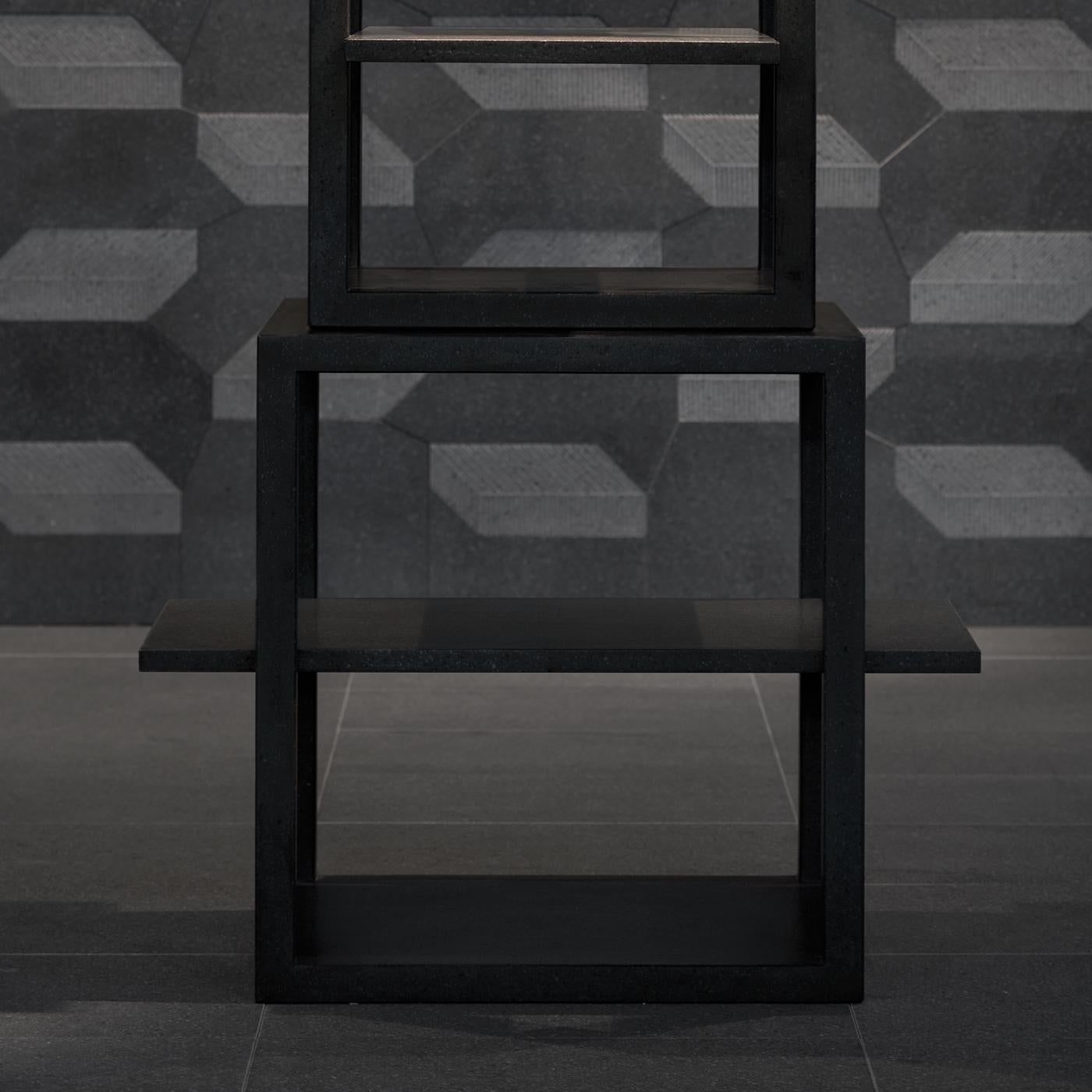 This contemporary bookshelf is entirely made of lava stone, fashioned by stacking four increasingly small and concentric hollow cubic shelves one on top of another. The trampolines protrude on horizontal axes, providing precious display surface. The