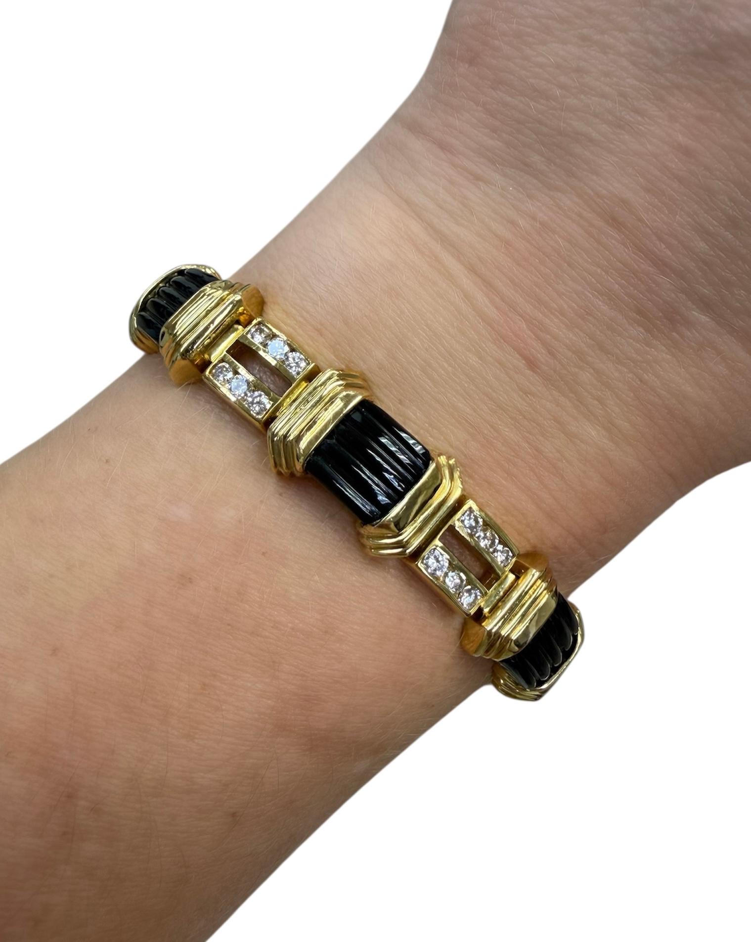 Ce bracelet de conception classique de La Triomphe contient 42 diamants ronds de taille brillant de première qualité pesant environ 2,50 carats au total, entrecoupés de sept onyx cannelés rectangulaires. Magnifiquement réalisé en or jaune 18 carats,