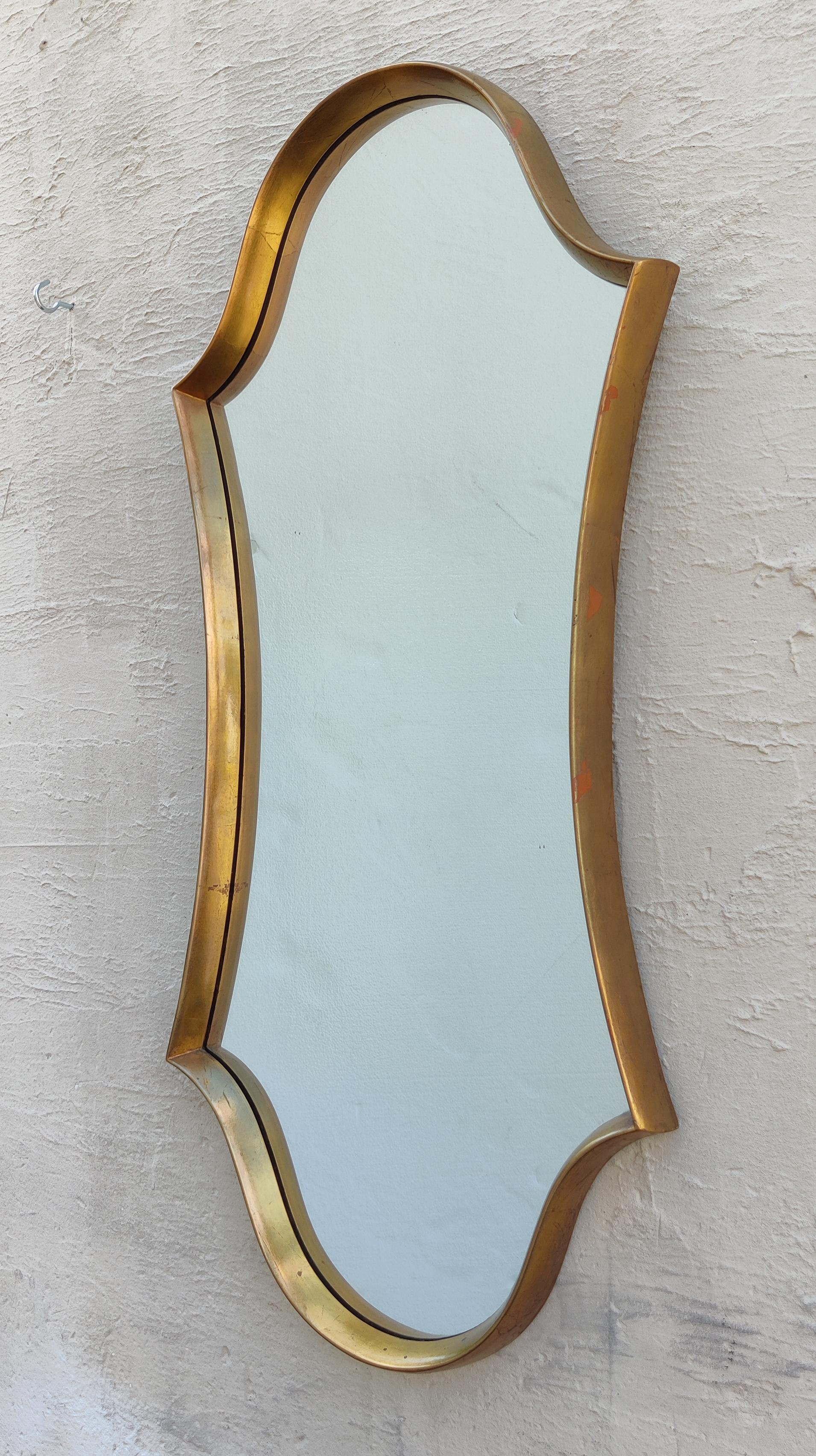 Attributed to LaBarge, this large mirror features a well-proportioned shield or crest shape with a carved and gilt wooden frame. A handsome accent piece for any modern home or hallway. 

In good vintage and original condition. No oxidation in mirror.