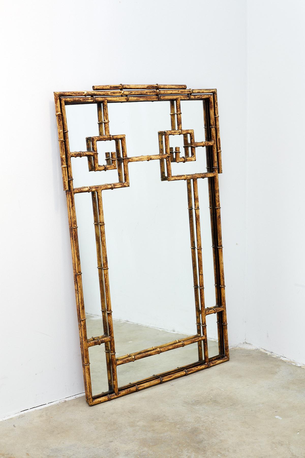 Stunning Hollywood Regency gilt iron mirror with a Chinese Chippendale style faux bamboo form. Featuring large Greek key designs and finished in a vintage gilt patina. Produced by Labarge, constructed in iron not wood. Very heavy and solid with