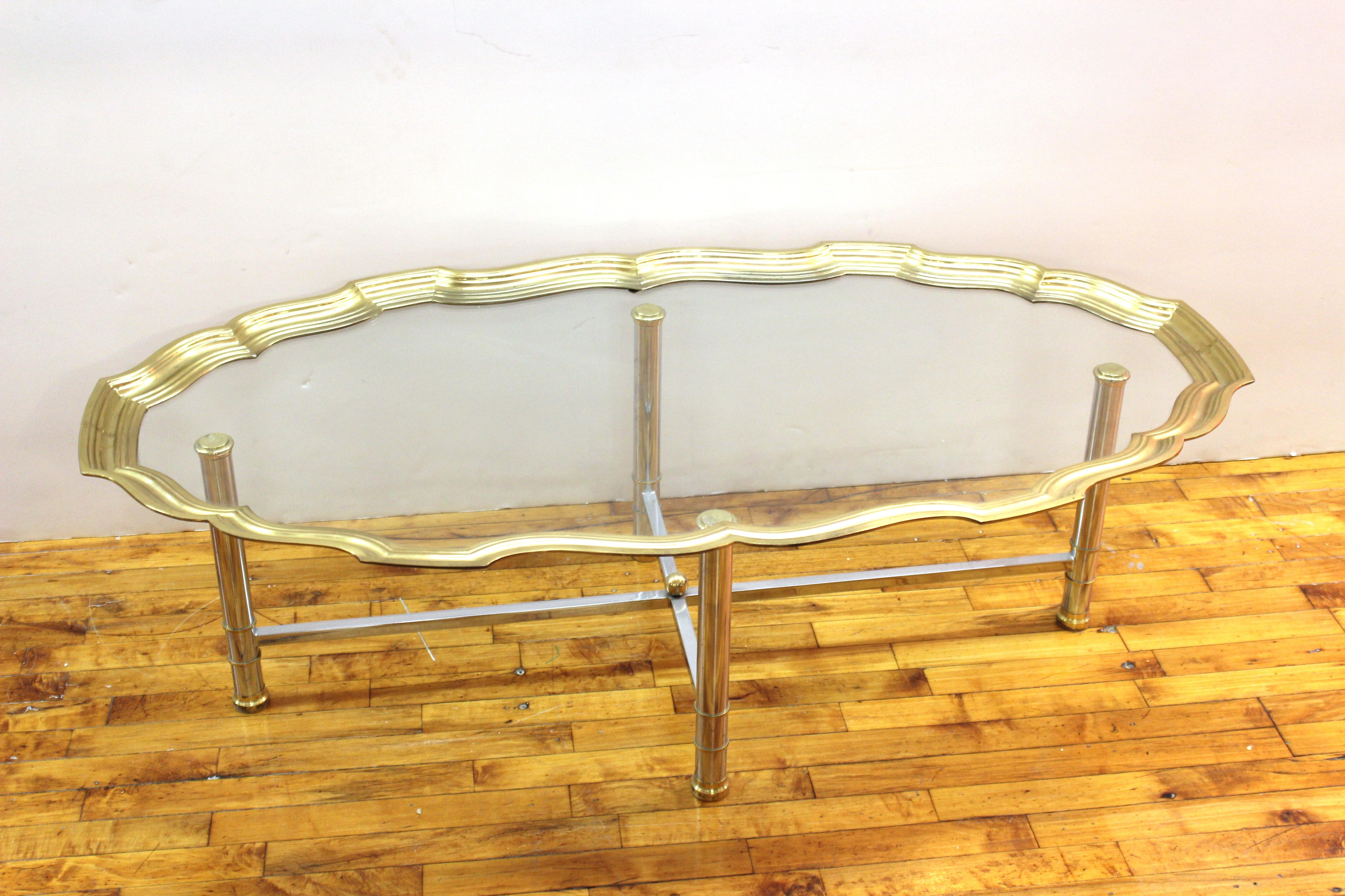 Hollywood Regency coffee or cocktail table designed by Labarge. The piece has a top with scalloped edges in brass around an oval glass top and sits on a chromed metal base. In great vintage condition with age-appropriate wear and use.