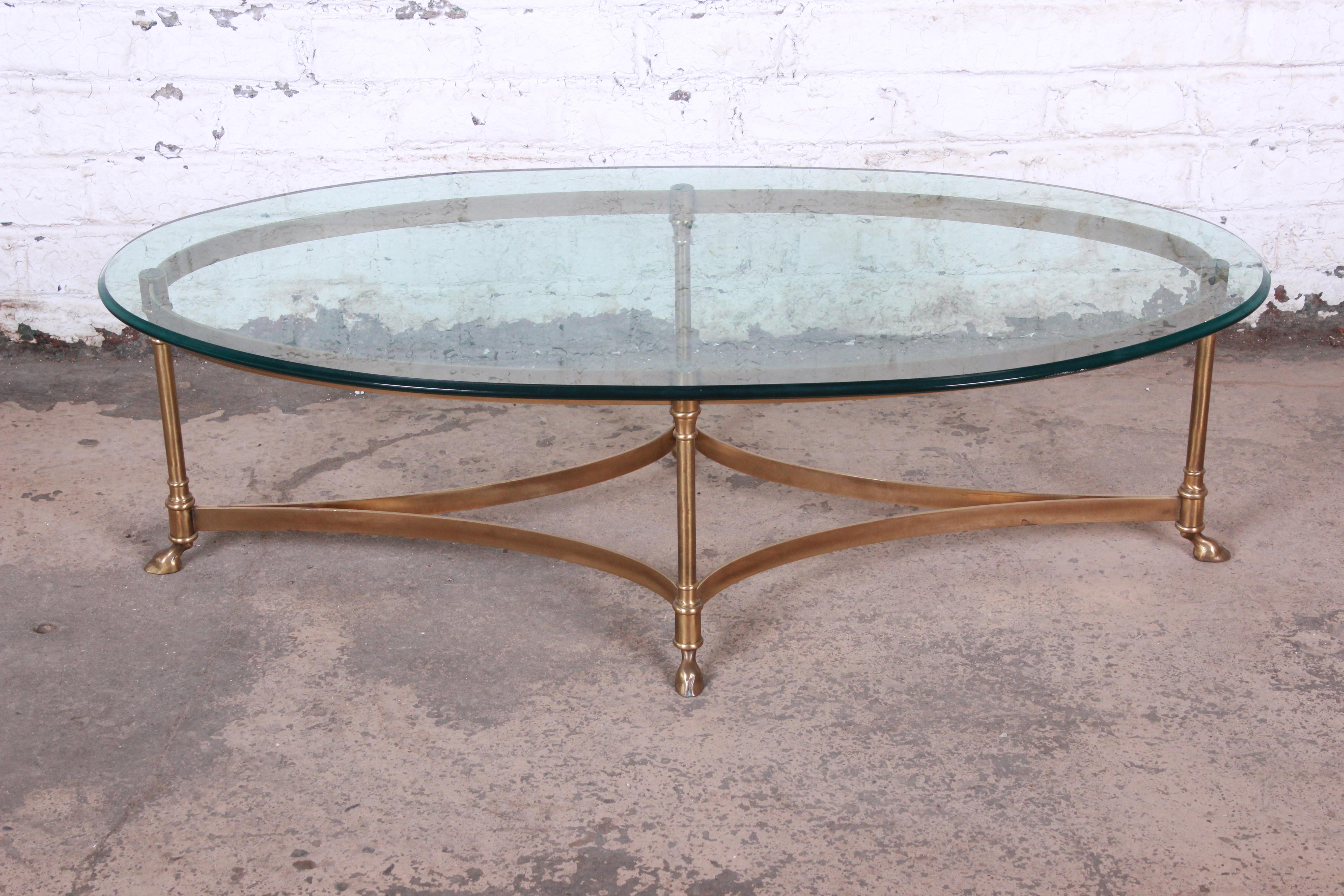 A gorgeous midcentury Hollywood Regency brass and glass coffee table by Labarge. The table features a stylish brass base with curved stretchers and unique hooved feet. The beveled glass top is in very good condition. Overall the table is in