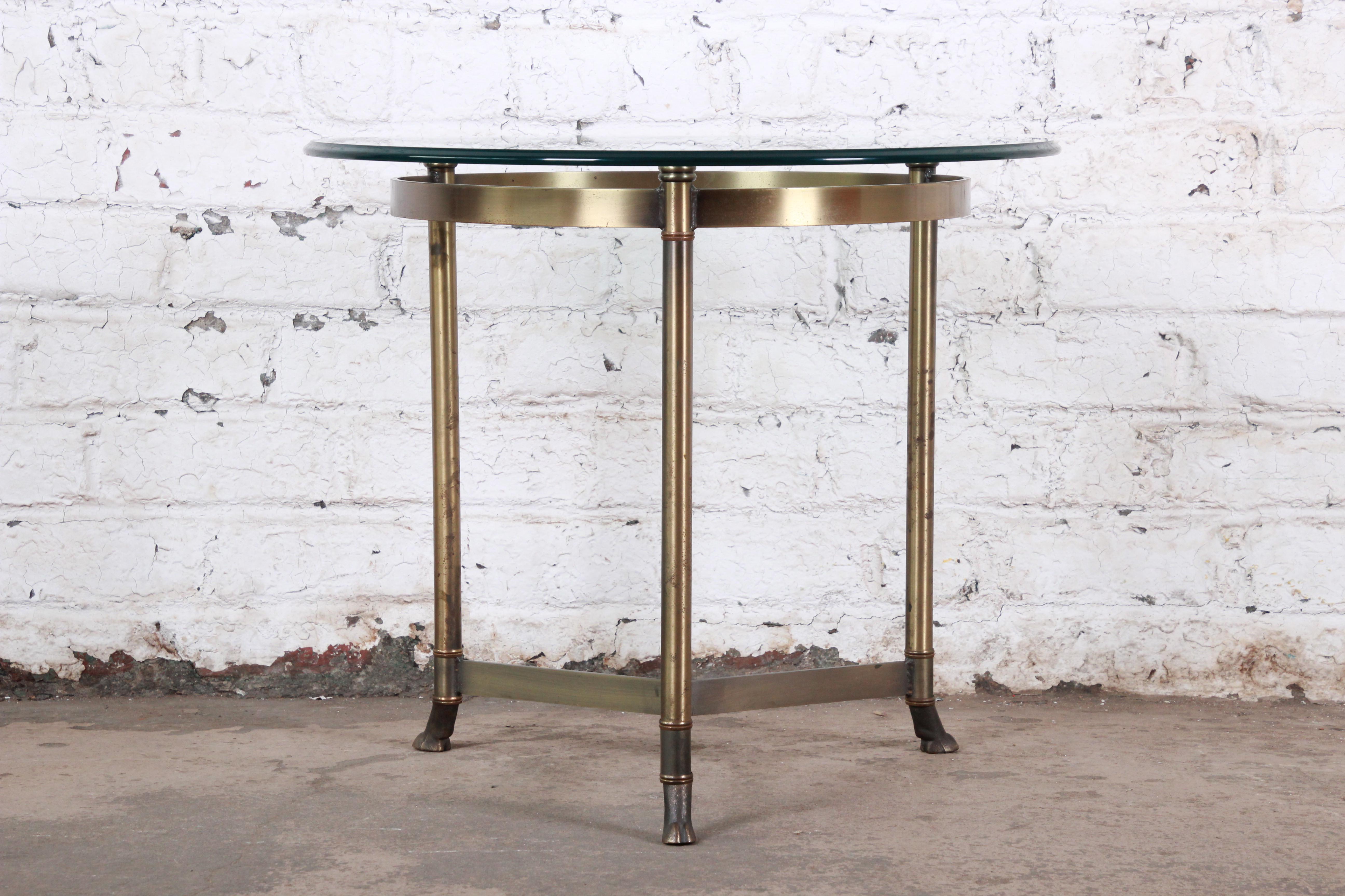 A gorgeous midcentury Hollywood Regency brass and glass side table by Labarge. The table features a stylish three-legged brass base with stretchers and unique hooved feet. The table is in very good original vintage condition.

The table measures