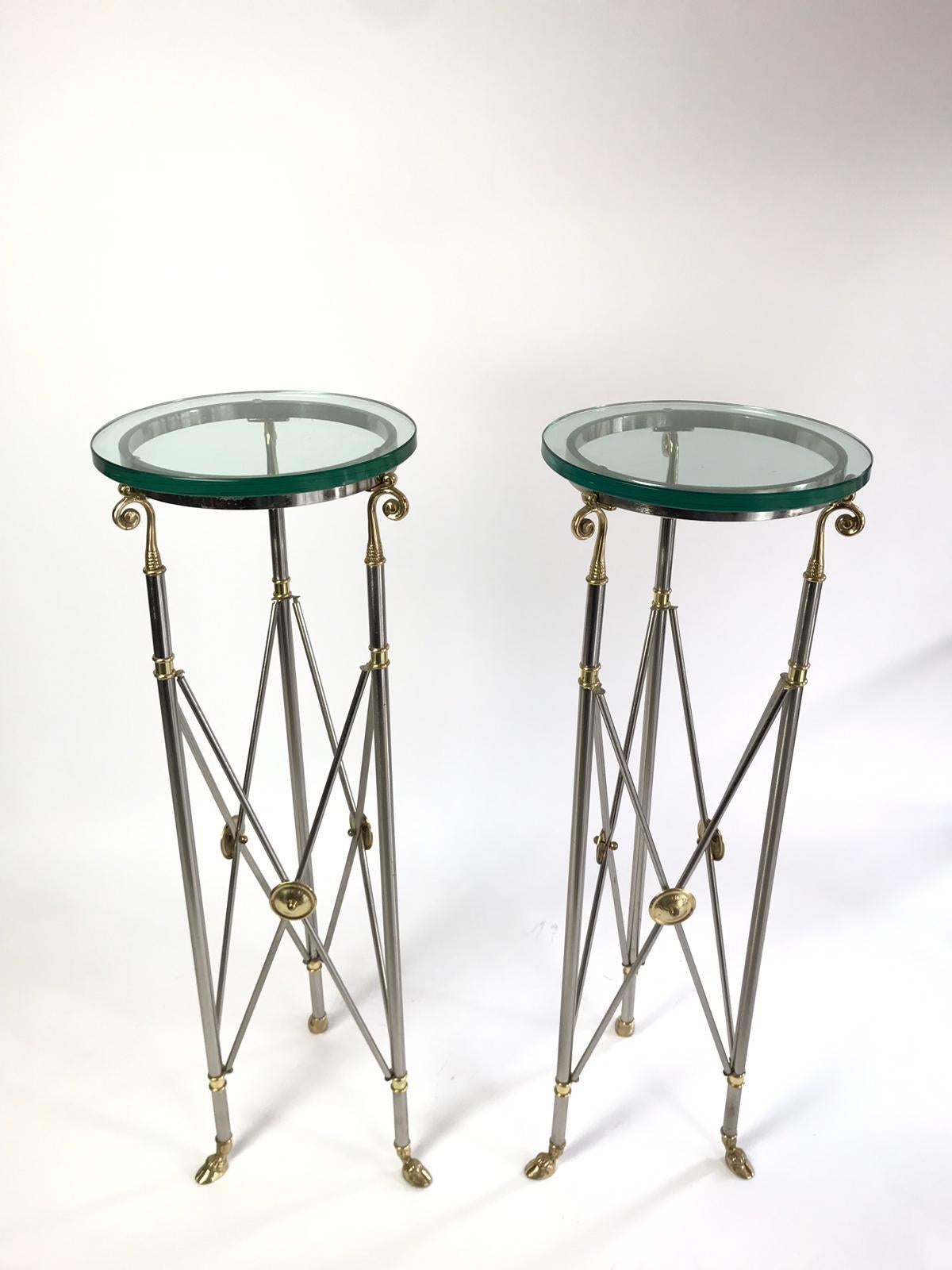 A fabulous pair of tall gueridon pedestals by Labarge. They are constructed in white metal and brass with brass hoof legs. They have a heavy thick piece of glass on top.