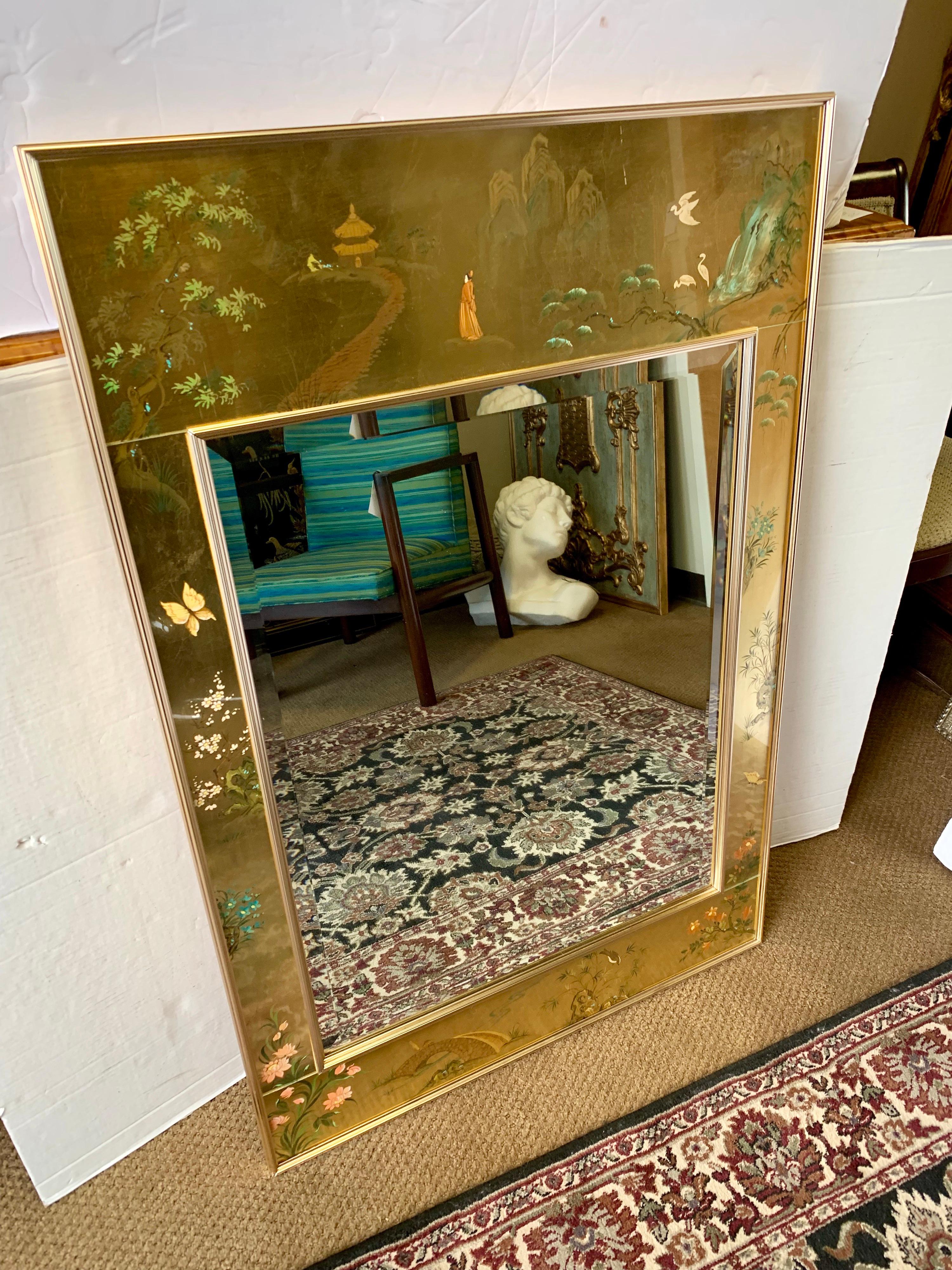 Midcentury Classic chinoiserie reverse hand painted and gold leaf framed beveled mirror with signature on bottom right. A brass frame surrounds the beveled mirror and the decorative band. Great detail, scale and size.