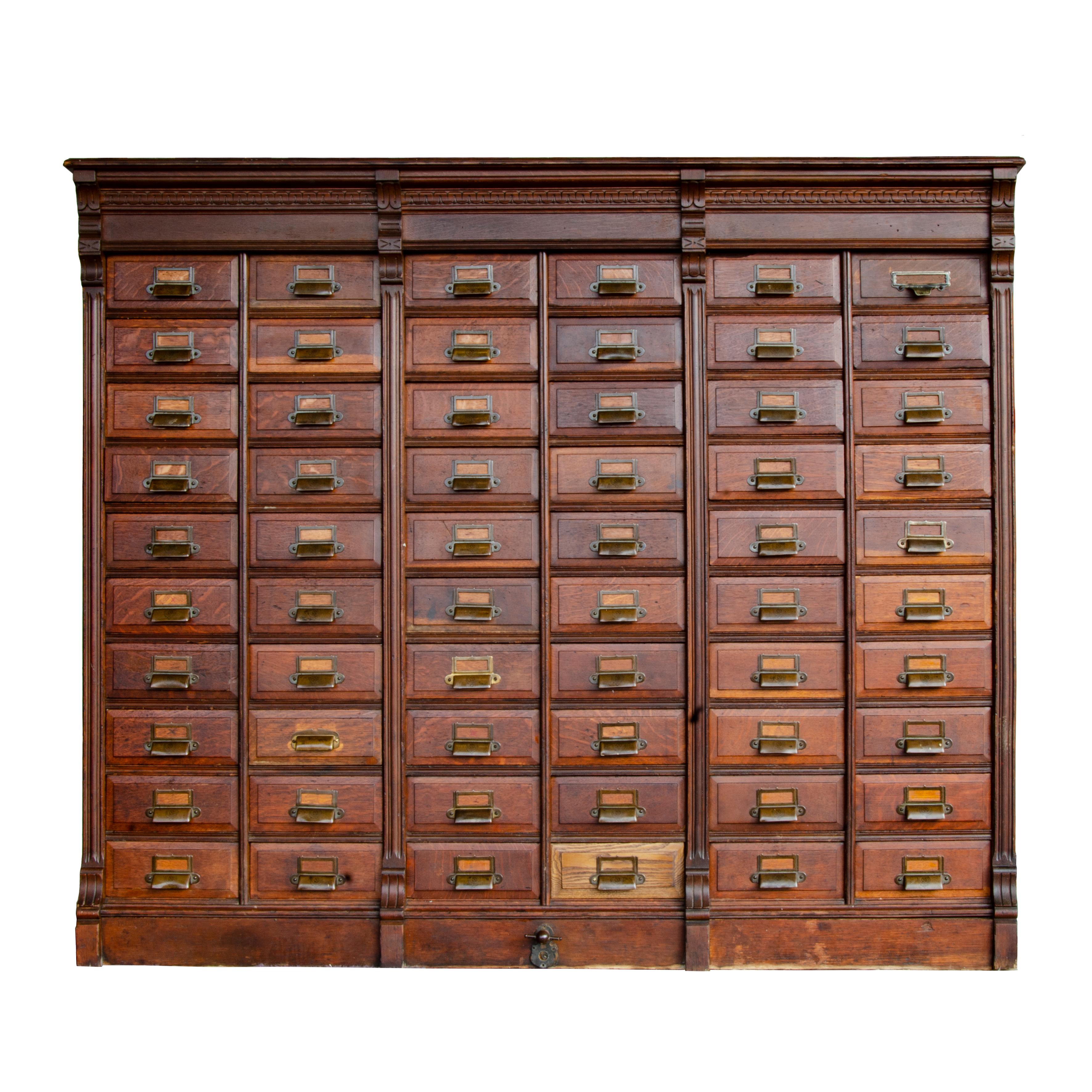 This magnificent multi-drawer cabinet is a handsome beast. Touches of detail in the reeded pilasters carved cornice nicely accent the piece’s brass bin pulls and fine oak graining. Manufactured by the Schlicht & Field Company, this piece is part of