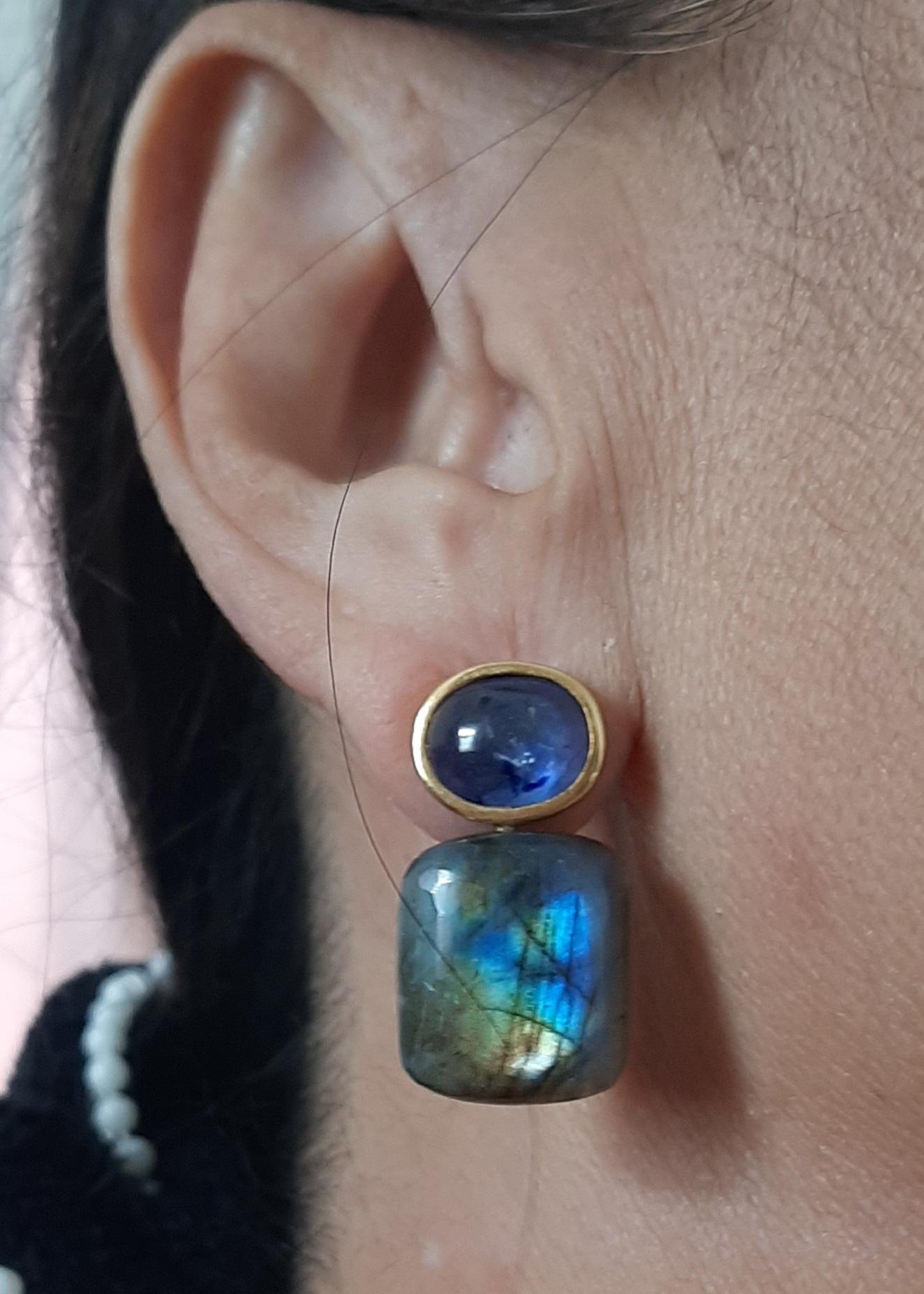 Diese einfachen, aber eleganten und handgefertigten Ohrringe bestehen aus 2 blauen Saphir-Cabochons mit den Maßen 8 x 10 mm, die in eine Lünette aus 14-karätigem Gelbgold gefasst sind, an der 2 Labradorite in Kissenform mit den Maßen 15 x 17 mm