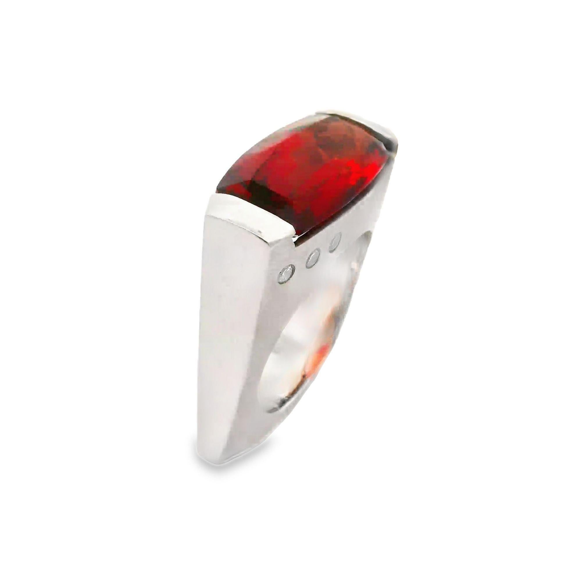 A striking red labradorite commands attention. Weighing 6.29 carats, the cushion-cut stone radiates a deep red-orange hue. Accentuated by 0.19 carats of round, white diamonds, the design is both bold and elegant. Crafted in 14k white gold, this
