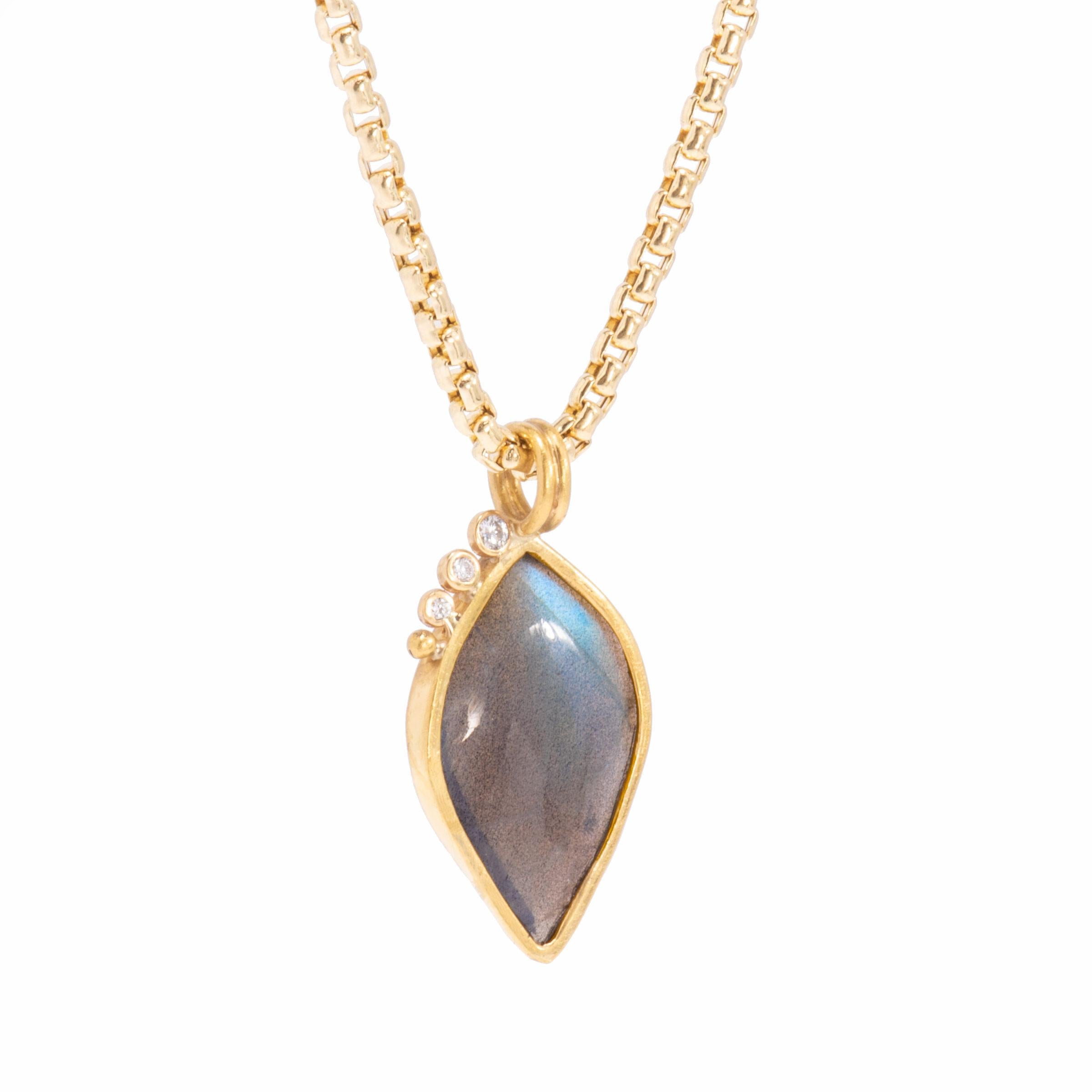 The Labradorite Leaf Pendant is set in an 18 karat gold frame and open in the back for clarity and a play of blue, green, lavender, yellow and silver lights. Crowned on one side with a descending row of 3 bright, white diamonds and an 18 karat gold