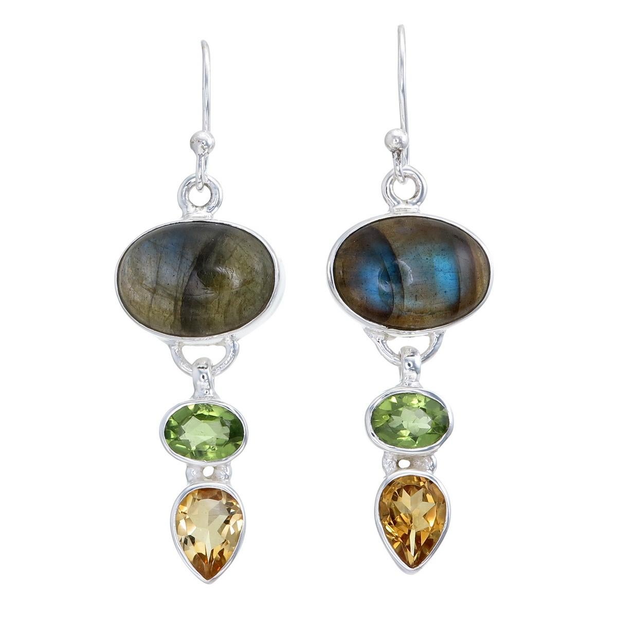 This handcrafted pair of sterling silver earrings showcases a harmonious blend of gemstones. The iridescent labradorite on top displays mesmerizing shades of blue and green. In the middle, the oval peridot adds a vivid green contrast, while the