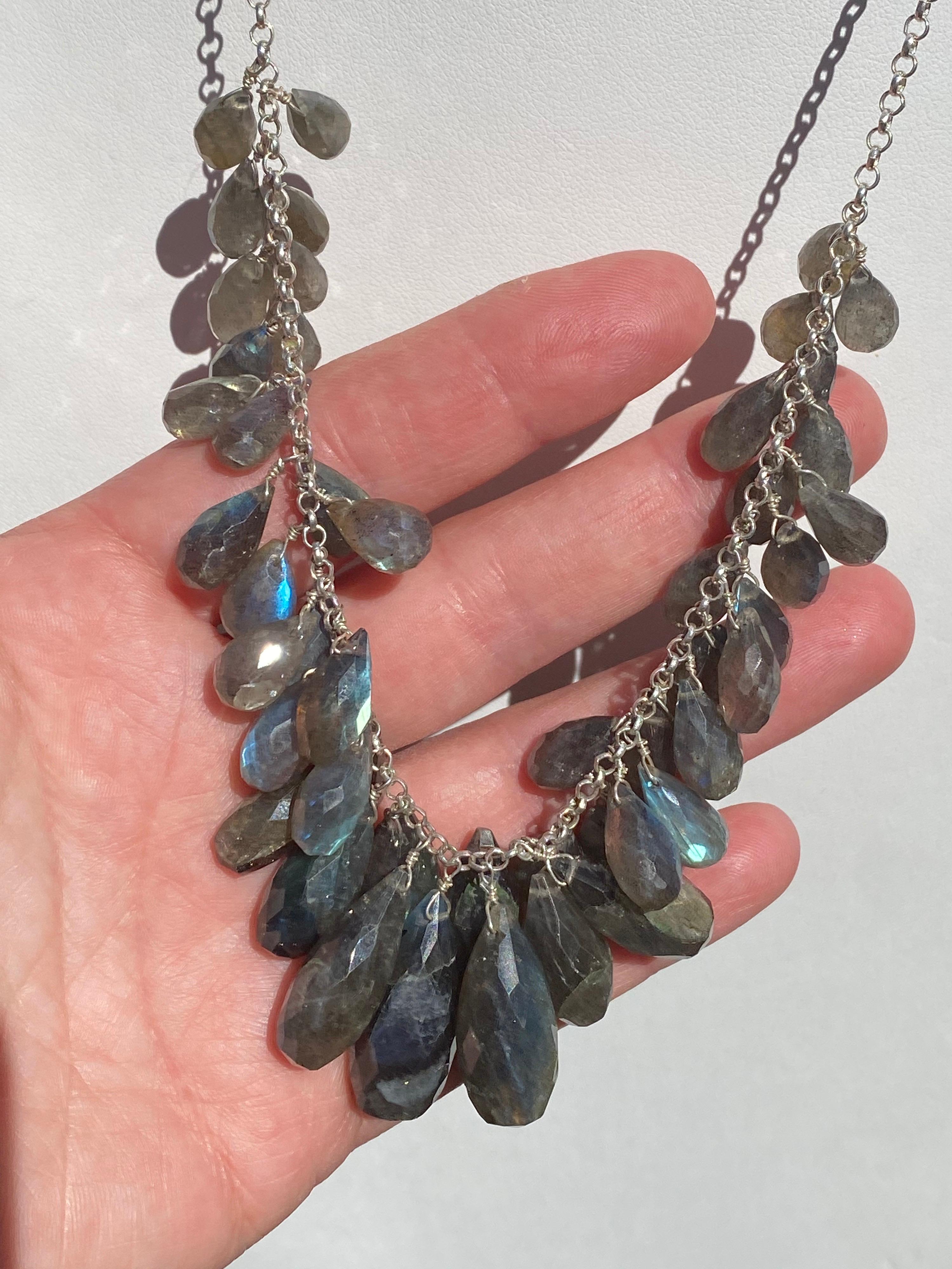 This is a lovely Sterling Silver necklace with 50 Briolette Labradorite Gemstones that are hand-wired wrapped and cascade down on the neck in a V-shape fashion. With flashes of Blue, Green, Grey, and some Golden Flashes make it mesmerizing to look