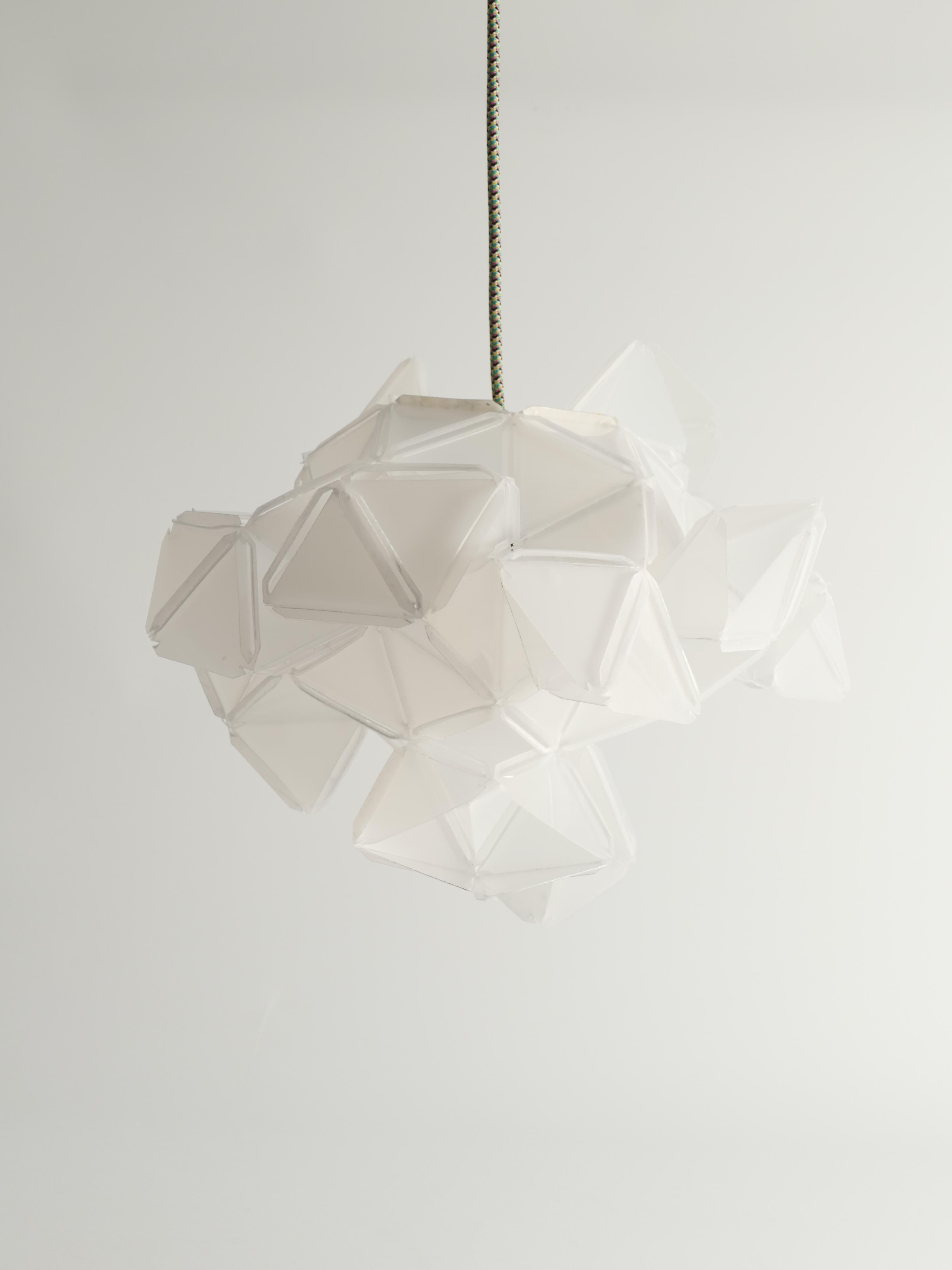 This artisan light sculpture Labyrinth, designed by Jakob Uhlin for By Republiken. Crafted from recycled plastic, this sculpture features triangular components that create a captivating, faceted appearance. The eleven identical protruding openings