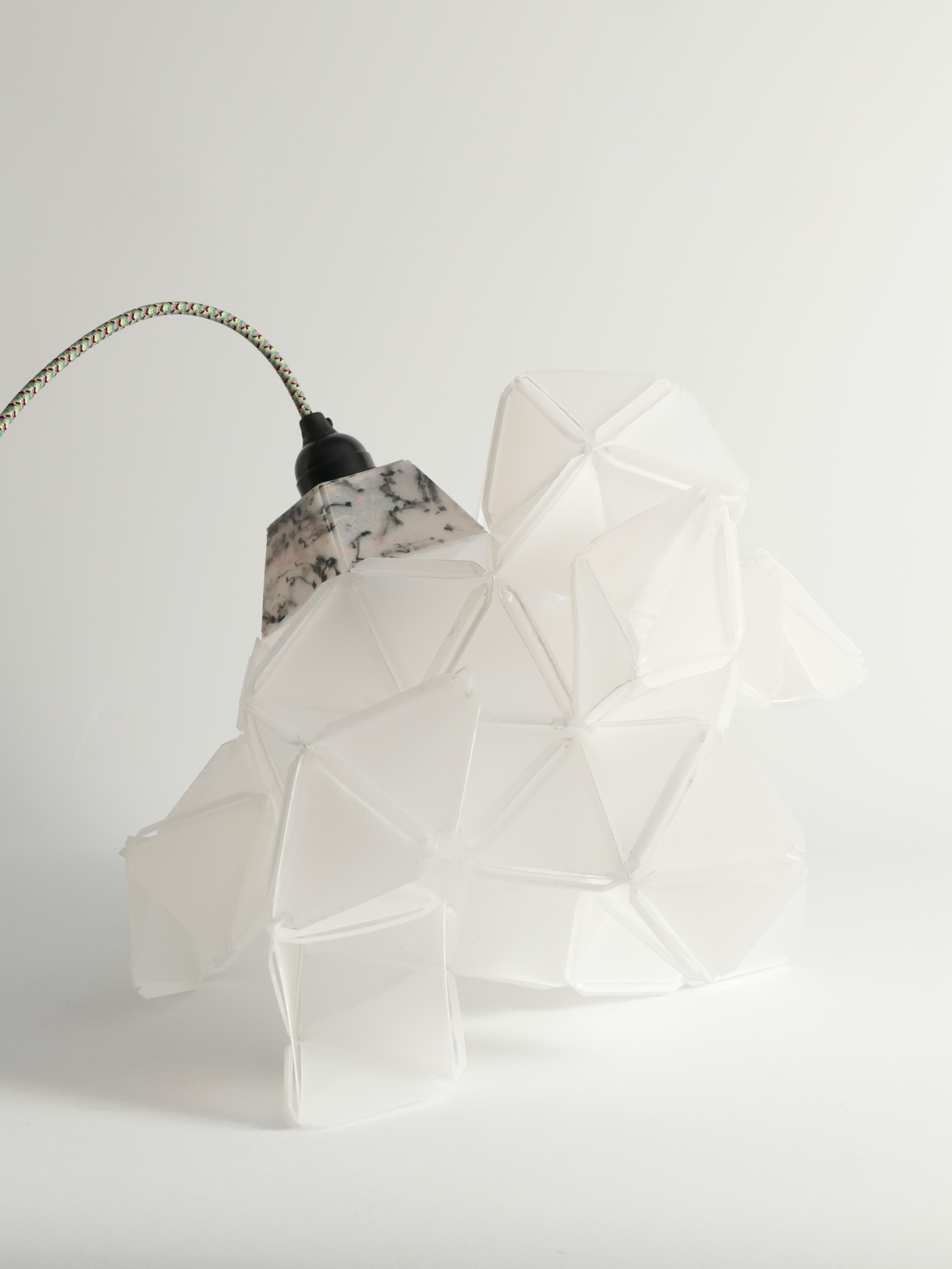 This artisan table lamp light sculpture Labyrinth, designed by Jakob Uhlin for By Republiken. Crafted from recycled plastic, this sculpture features triangular components that create a captivating, faceted appearance. The eleven identical protruding