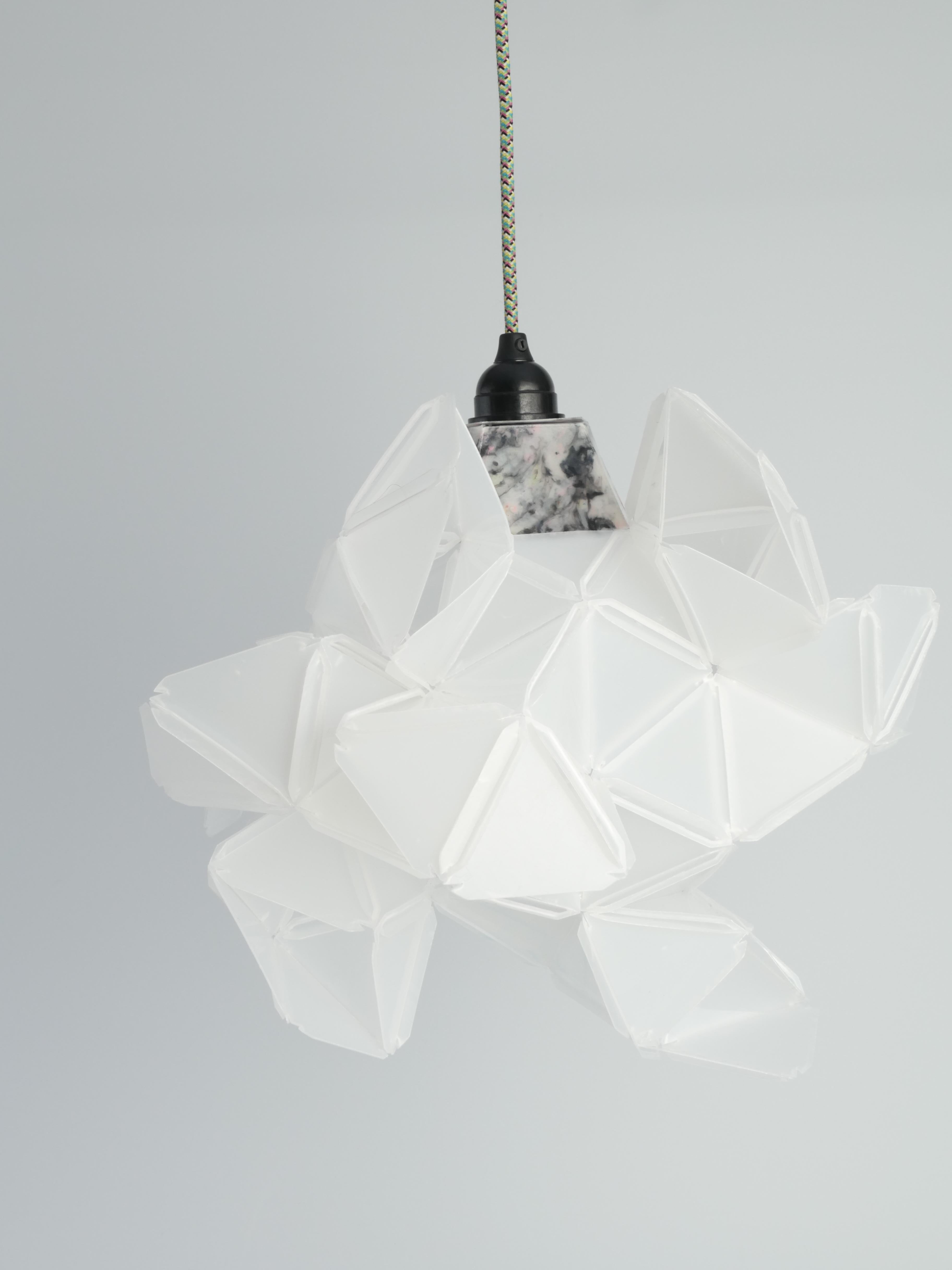 This artisan light sculpture Labyrinth, designed by Jakob Uhlin for By Republiken. Crafted from recycled plastic, this sculpture features triangular components that create a captivating, faceted appearance. The eleven identical protruding openings