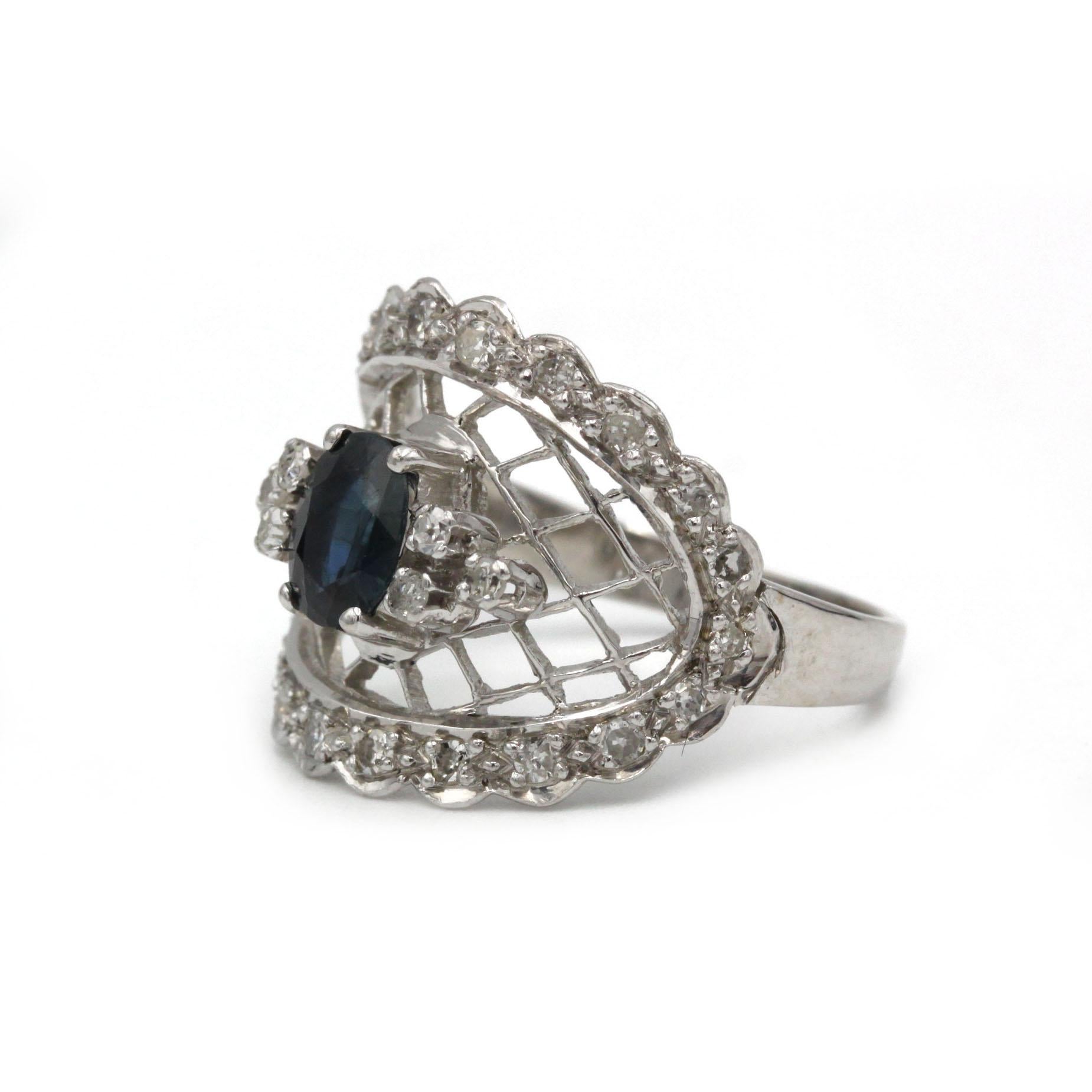 Dieser zarte Ring mit Spitzenmotiv aus leuchtendem 18-karätigem Weißgold (750‰) zeichnet sich durch einen ovalen tiefblauen Saphir von 0,80 Karat aus, der von anmutigen Zacken gehalten wird. Den zentralen Edelstein umgibt ein feines durchbrochenes