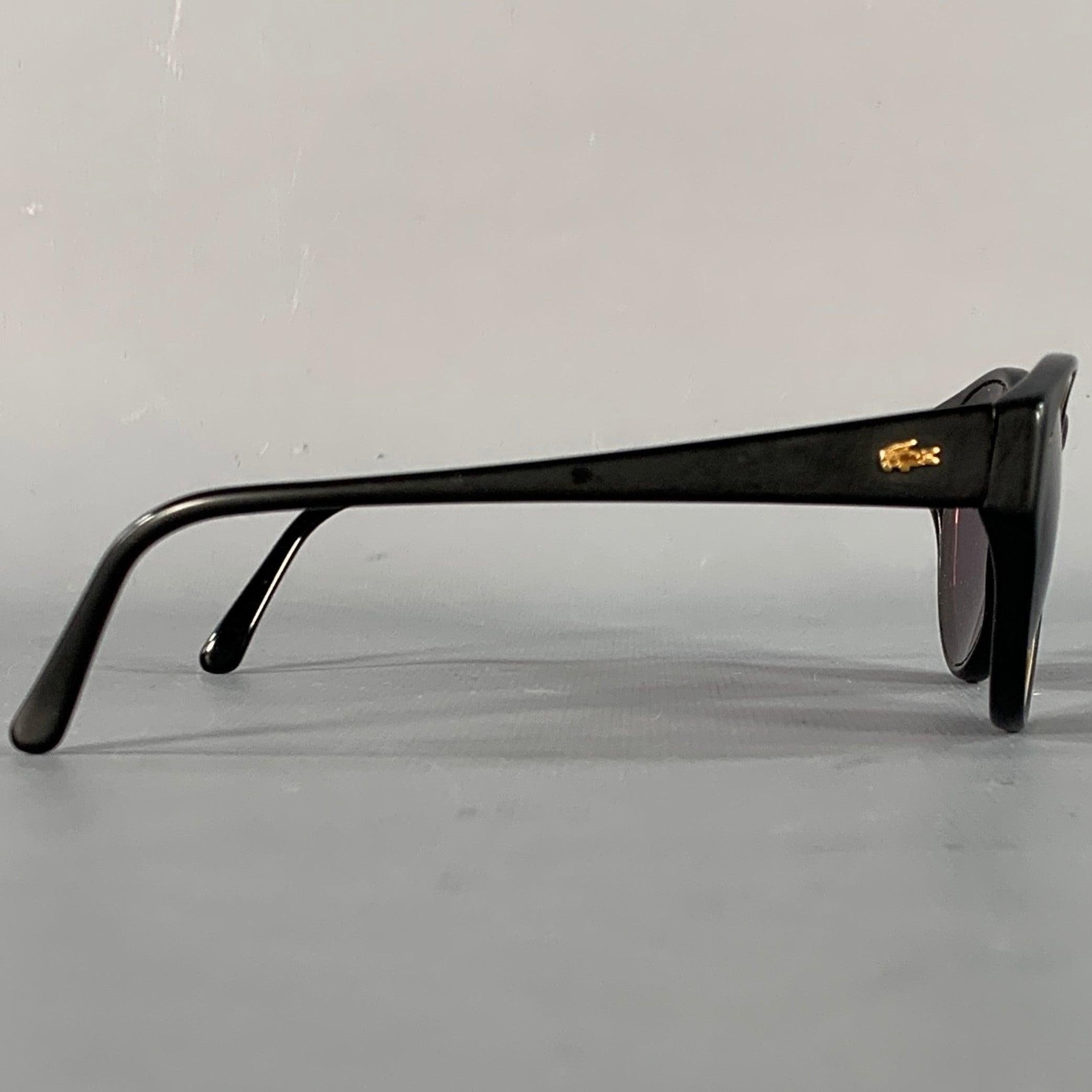 LACOSTE-Sonnenbrille
aus schwarzem Acetat mit goldfarbenem Metallakzent, runder Form und getönten Gläsern. Ausgezeichneter Pre-Owned Zustand. 

Markiert:   124 

Abmessungen: 
  Rahmenbreite: 13,75 cm.Rahmenhöhe: 4,5 cm.
  
  
 
Sui