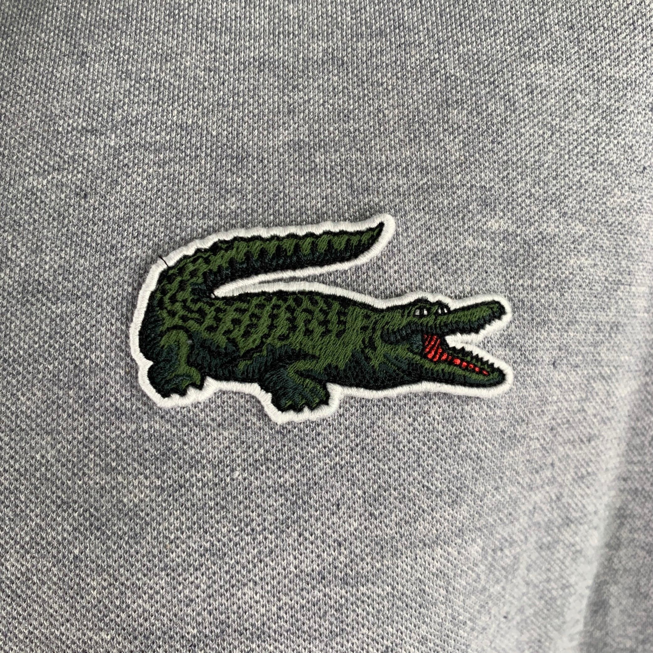 LACOSTE polo in a grey cotton fabric featuring a loose fit, large alligator patch, and hidden half placket button closure. Excellent Pre-Owned Condition. 

Marked:   FR 4 

Measurements: 
 
Shoulder: 18 inches Chest: 45 inches Sleeve: 9 inches