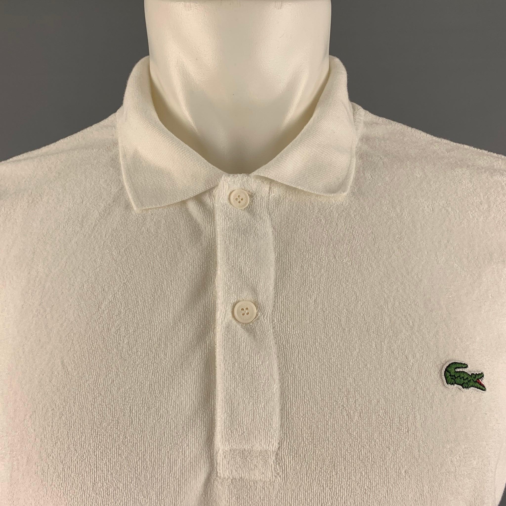 LACOSTE
 polo comes in a white cotton terry cloth material featuring a spread collar and a half buttoned closure.Very Good Pre-Owned Condition. 

Marked:   M 

Measurements: 
 
Shoulder: 18 inches Chest: 43 inches Sleeve: 9 inches Length: 27 inches 