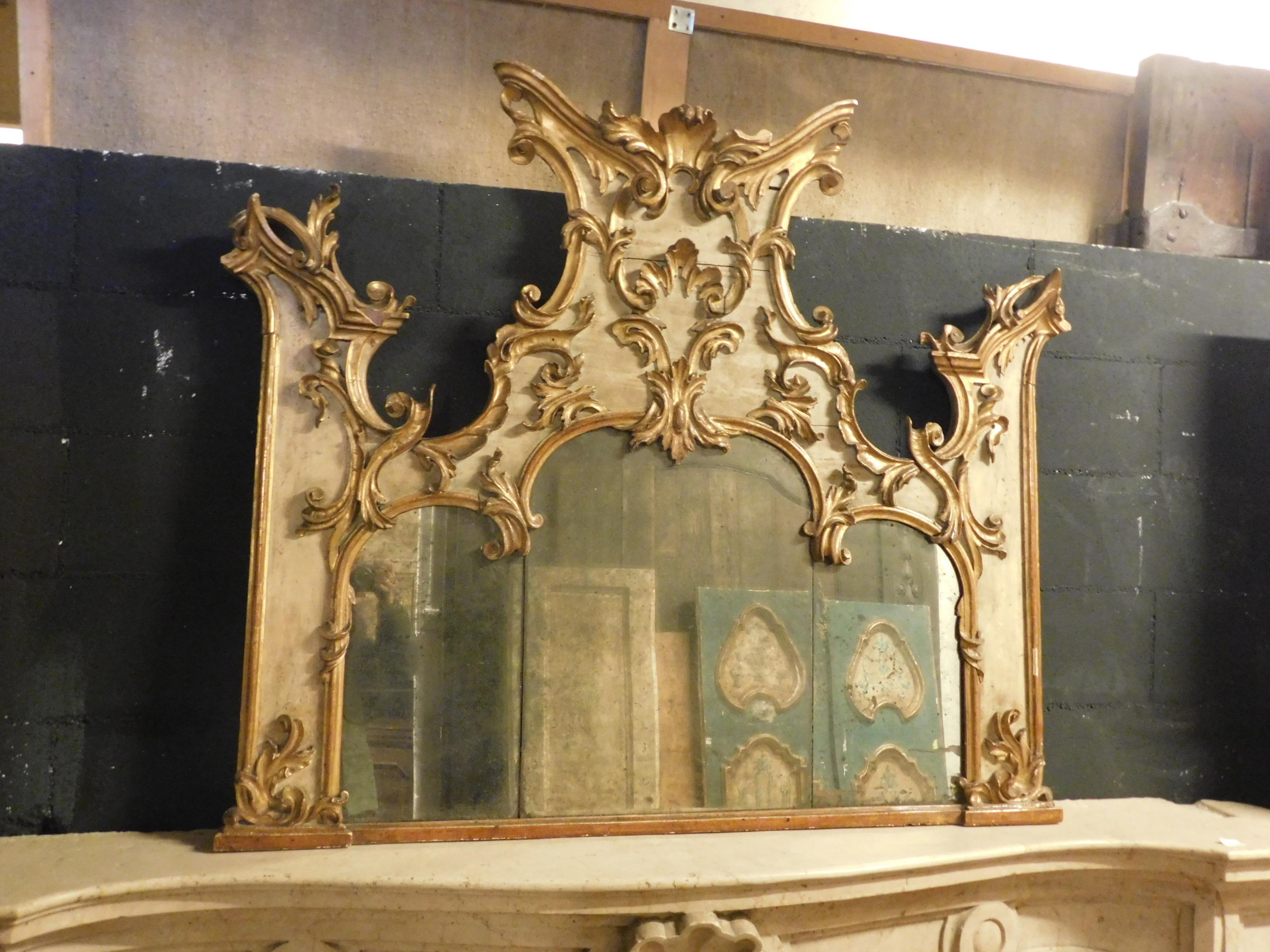 Ancient and important hand-lacquered mirror with beige and golden color, richly carved and sculpted in the part of the wooden frame, with sculptures of spiers and decorations from a rich mirror above the fireplace. Built entirely by hand in the 19th