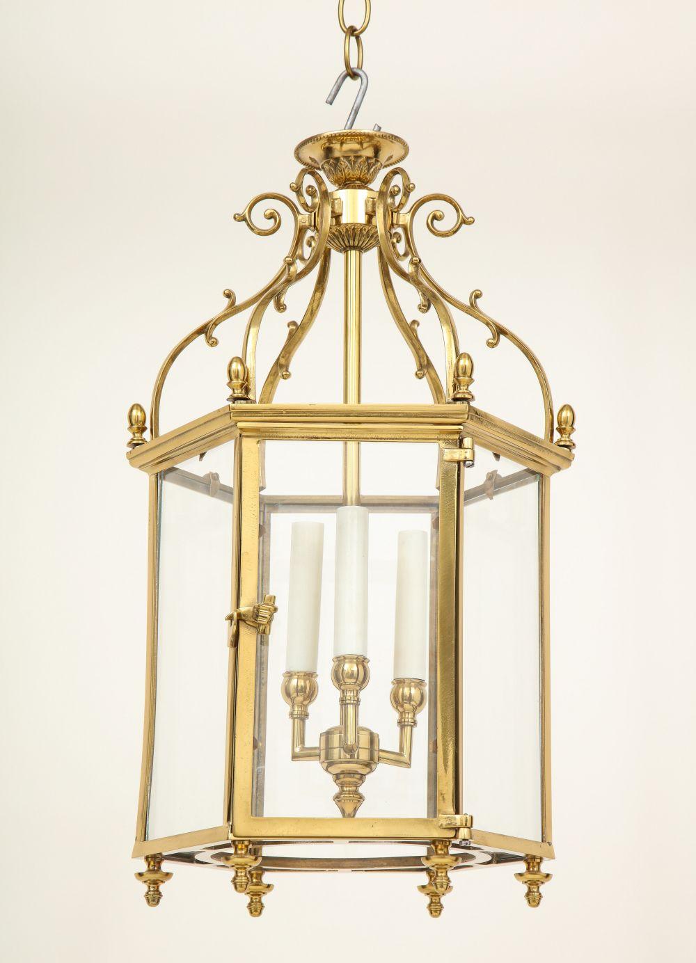 Fitted with four electrified candlelights within the hexagonal glass-inset frame, with volute scroll cresting.