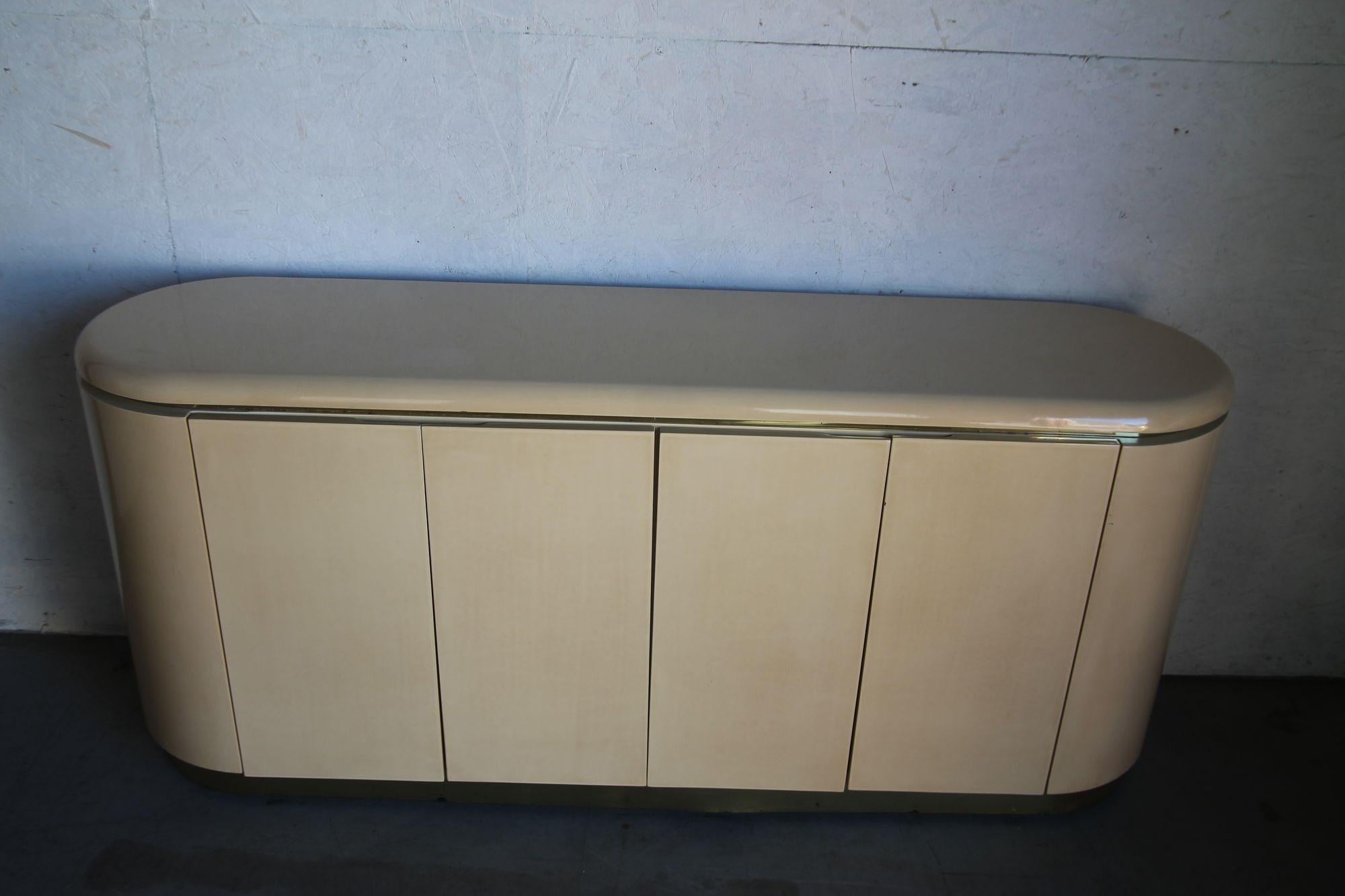 Cremefarben lackierter Schrank, Karl Springer zugeschrieben. Dieser Schrank hat eine Schublade und ein Regal auf jeder Seite des Schranks, wie auf den Fotos gezeigt. In natura ist es ein sehr beeindruckendes Stück. Ist in schönem Vintage-Zustand mit