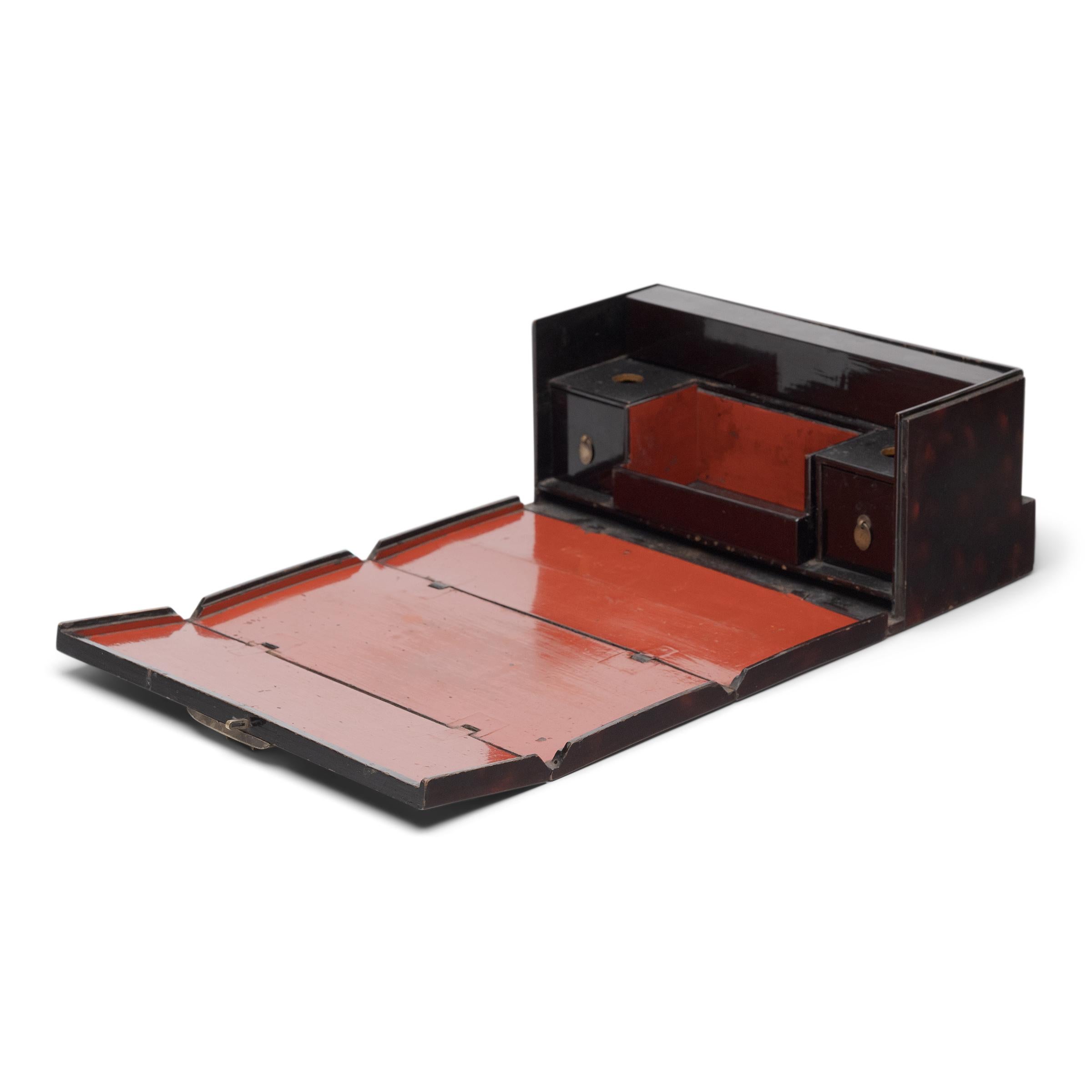 This small lacquered box is actually a portable opium kit, used to hold all the accessories one might need when smoking opium. The exterior is decorated with brushed lacquer in imitation of tortoise shell, while the interior is cloaked in vibrant