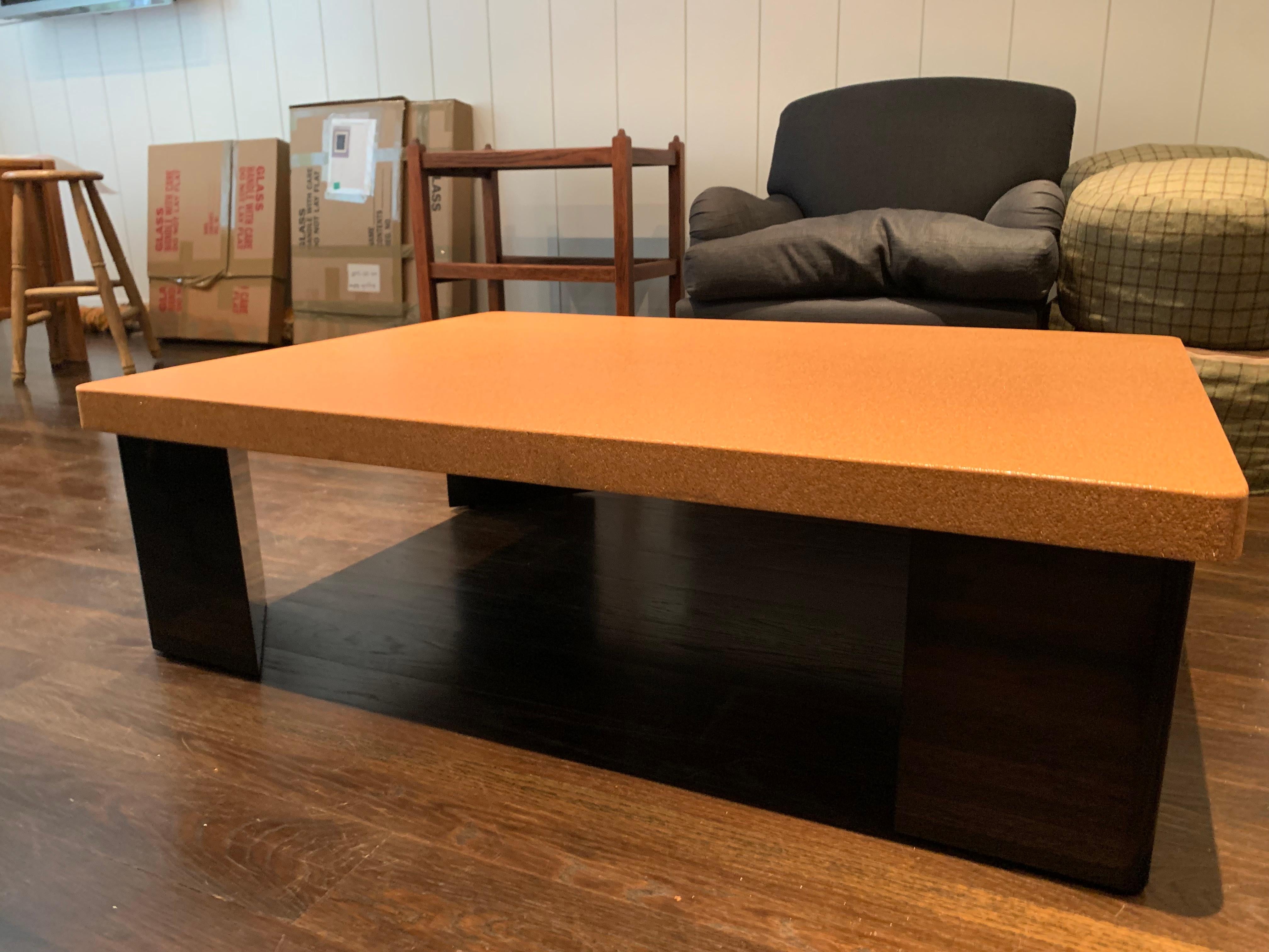 Table basse conçue sur mesure avec un plateau en liège laqué brillant et des pieds noirs.