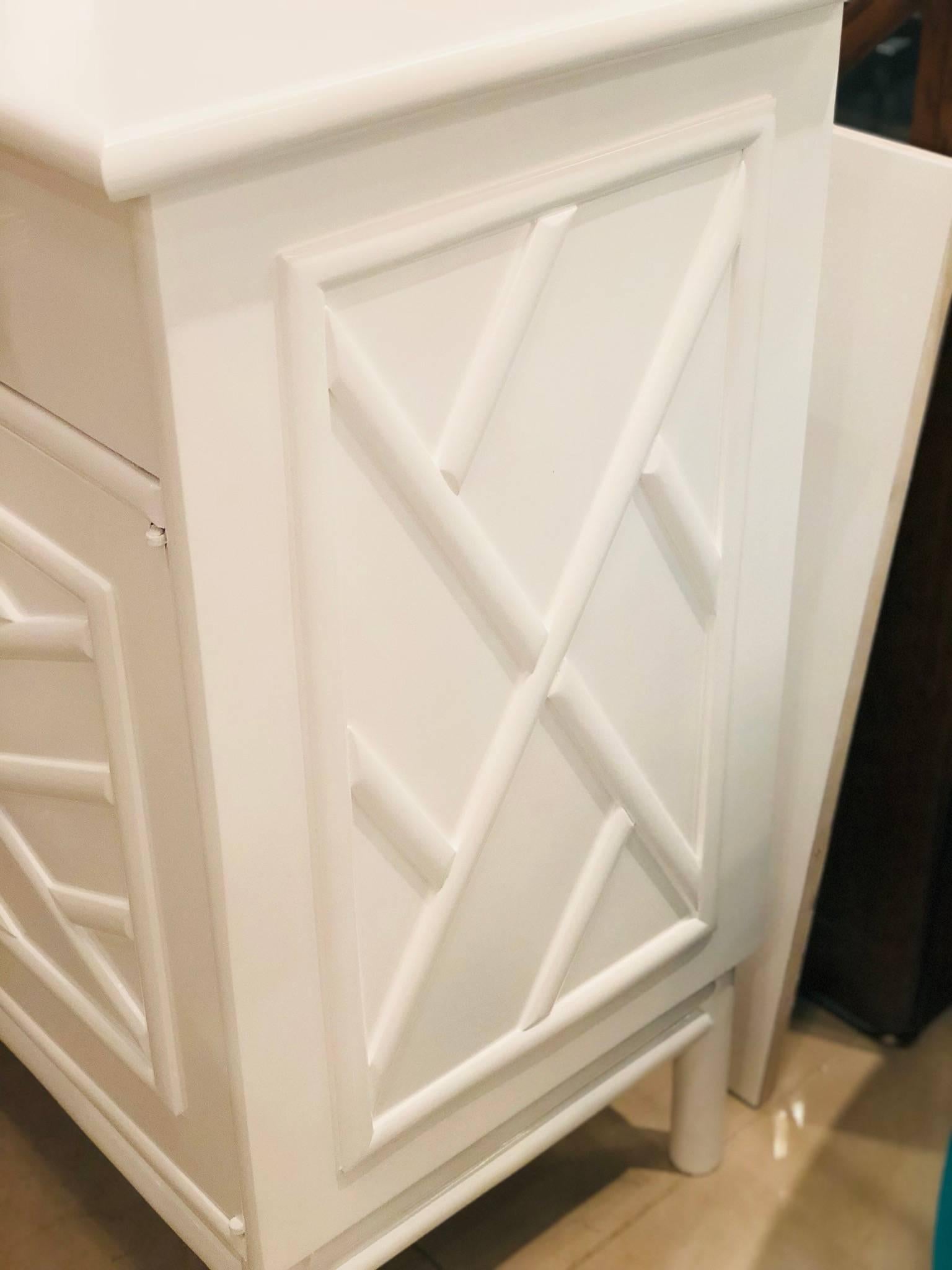 Amazing vintage newly lacquered white Credenza, Buffet, Sideboard. Rattan, Faux Bamboo Chinese Chippendale details. Oversized Lucite and brass hardware. There are two drawers on top and the doors open to reveal a shelf on each side. Lacquered inside