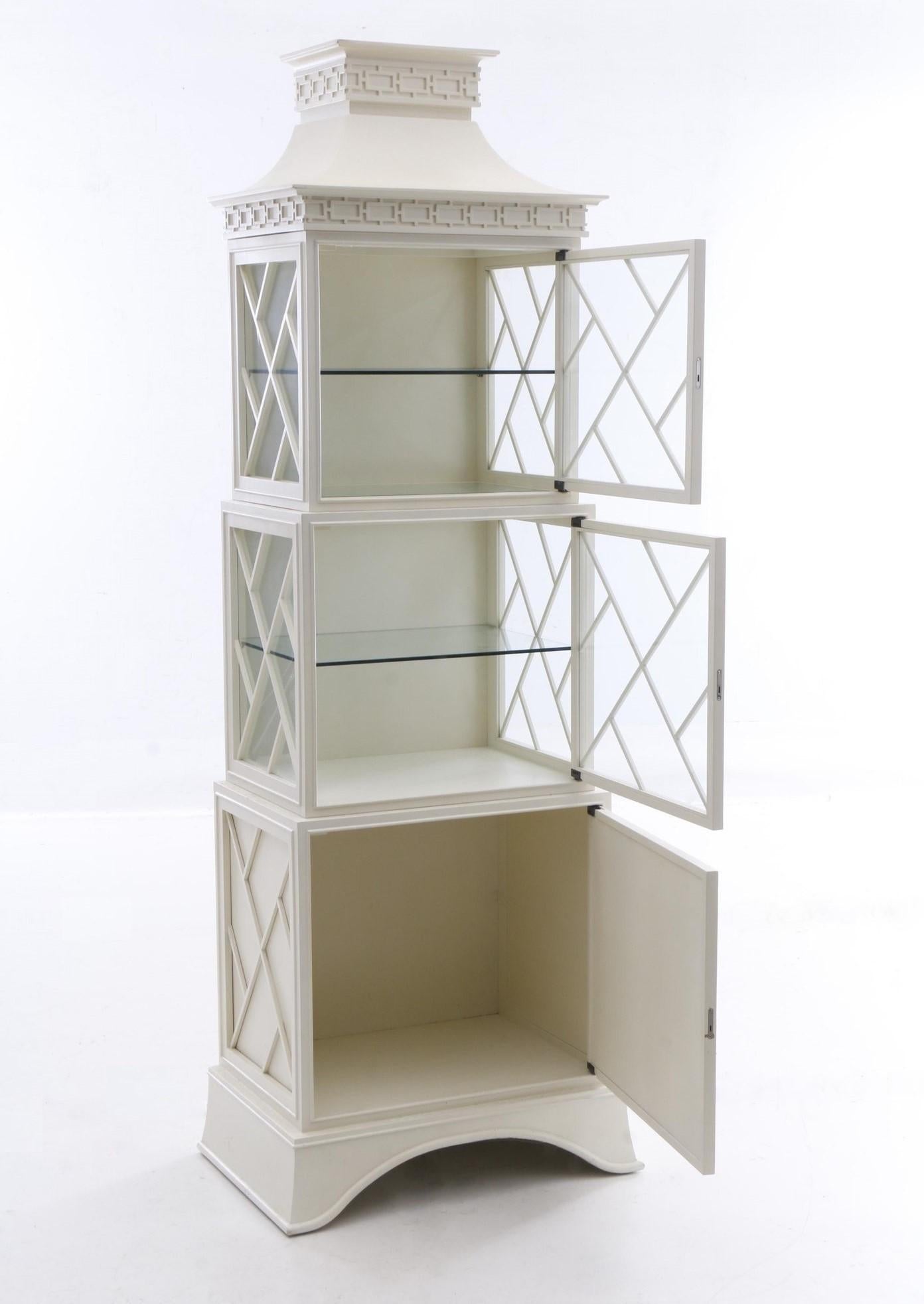 Timeless Chippendale's Chinese-style fretwork beautifully incorporated in this modern day lovely lighted display cabinet featuring wooden construction in a cream lacquer finish. This piece has a pagoda top over a graduated arrangement of three