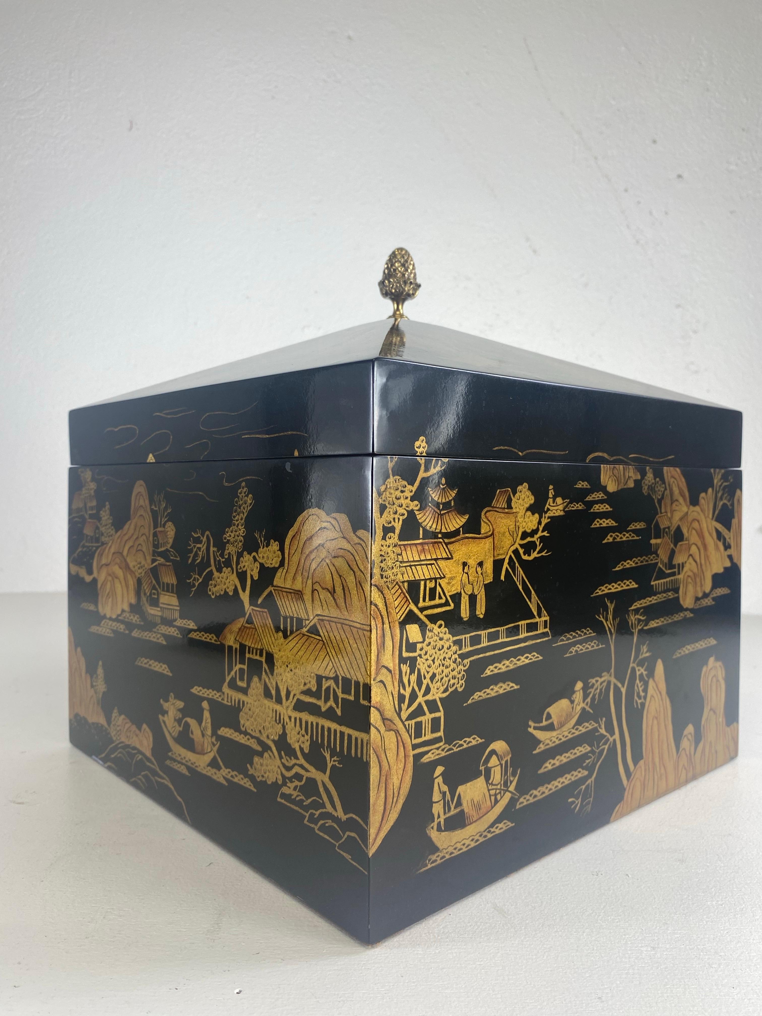 This is a vintage Lacquered chinoiserie chest by Maitland Smith. This Lacquered chest has a black background with hand painted Chinese scenes in gold around the entire surface of the chest. This large box has a diamond shaped lid with a solid breast