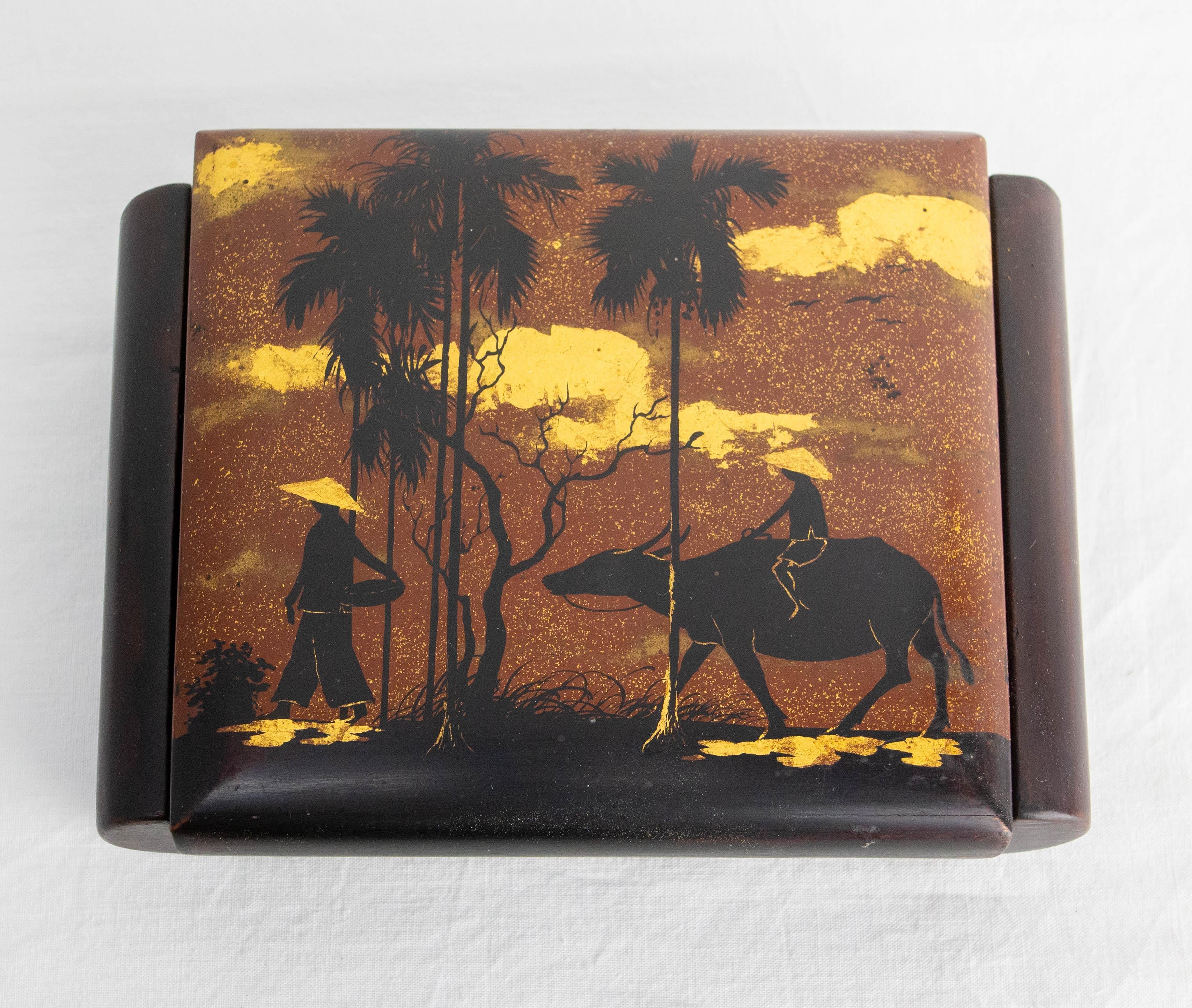 Little lacquered white wood jewels box, with a mirror inside.
Red velvet covering the inside of the box. Made circa 1960

The lid features two peasants on the road. One is riding a buffalo.
They are crossing a landscape adorned with palm