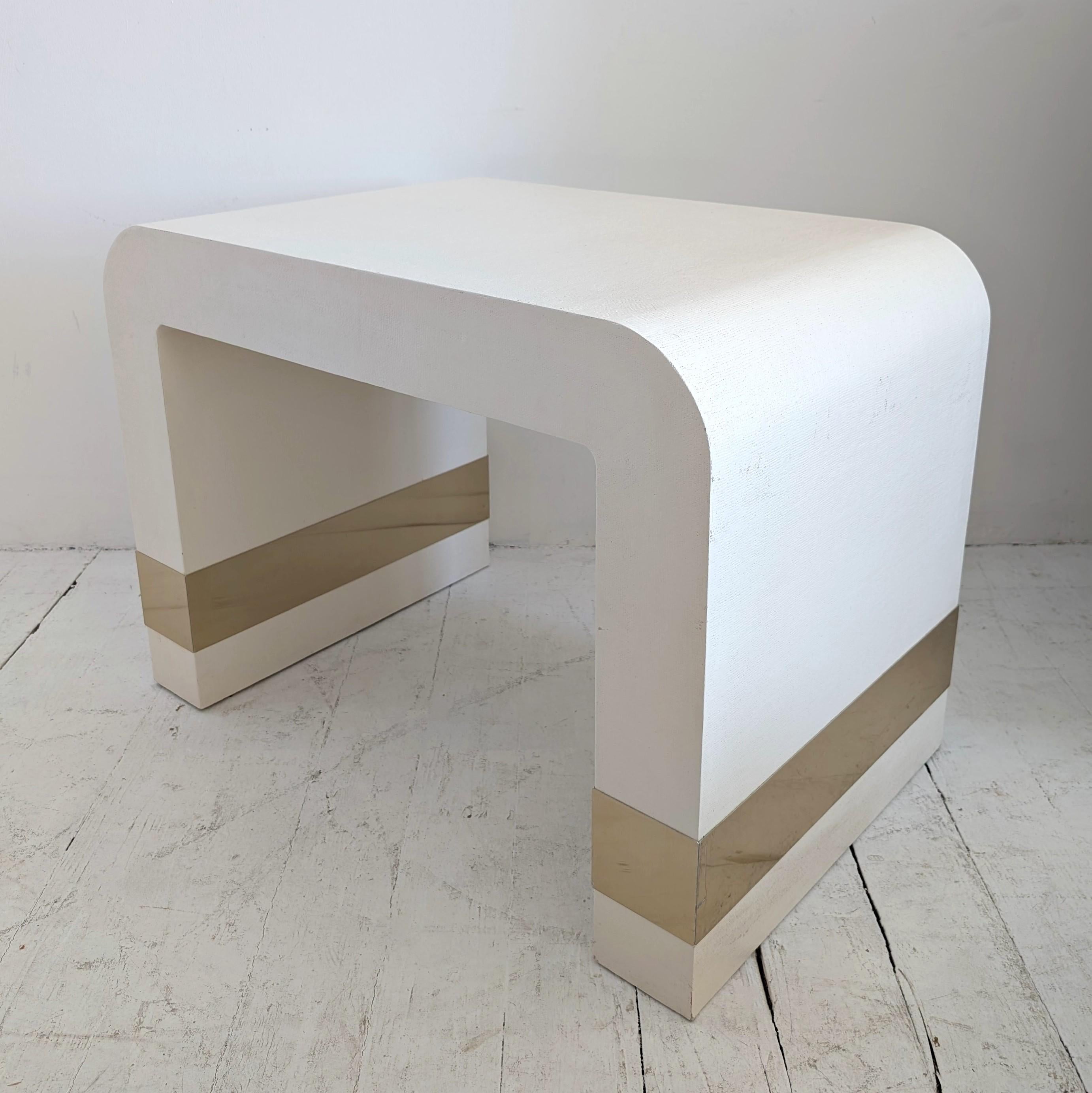 Lacquered off white linen waterfall side or coffee table with gold metal bands, USA 1980s. Karl Springer style.

A few little scuffs to the metal bands.

Dimensions: width 82cm, depth 51cm, height 59cm