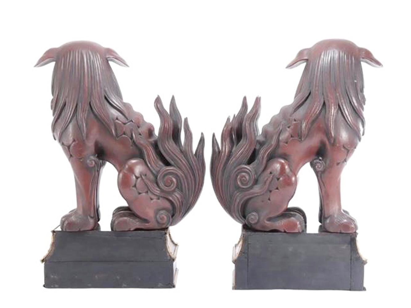 Pair of Japanese lacquered wood figures depicting seated Foo Dogs or Guardian Lions in a deep red-brown lacquer with stylized mane and tail, having reverse painted glass eyes and seated on French style Boullework stands.