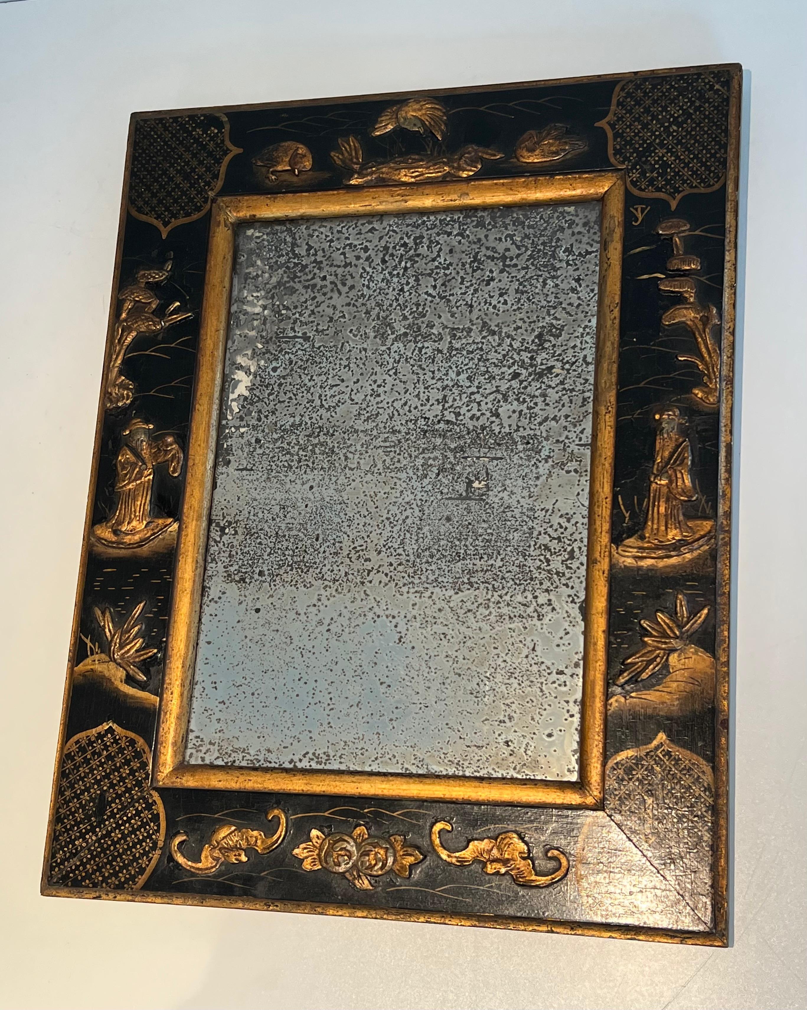 This very nice mirror is made of an old mercury mirror surrounded by a wooden frame beautifully lacquered and gilding with Chinese scenes. This is a French work in the style of Maison Jansen. Circa 1940