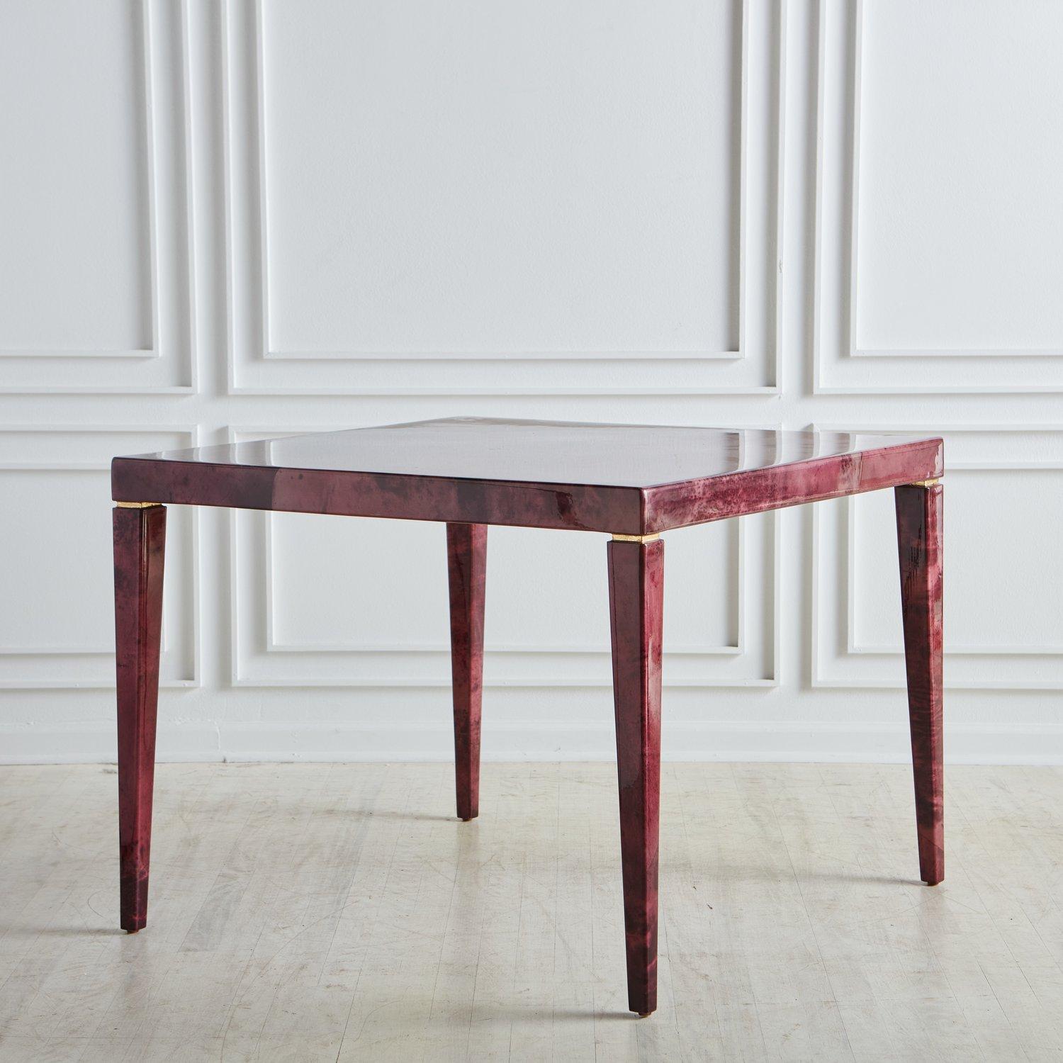 A captivating square dining table designed by Enrique Garcel. This table features a lacquered parchment finish dyed in a deep plum hue with natural patterns and subtle color variations. It stands on four square tapered legs with subtle hand applied