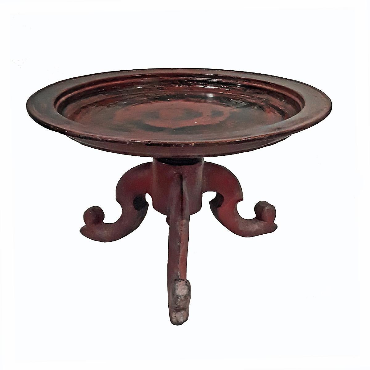 A late 19th century pedestal server / low table, hand carved in Thailand. Red and black lacquer, with a patina conferred by time.