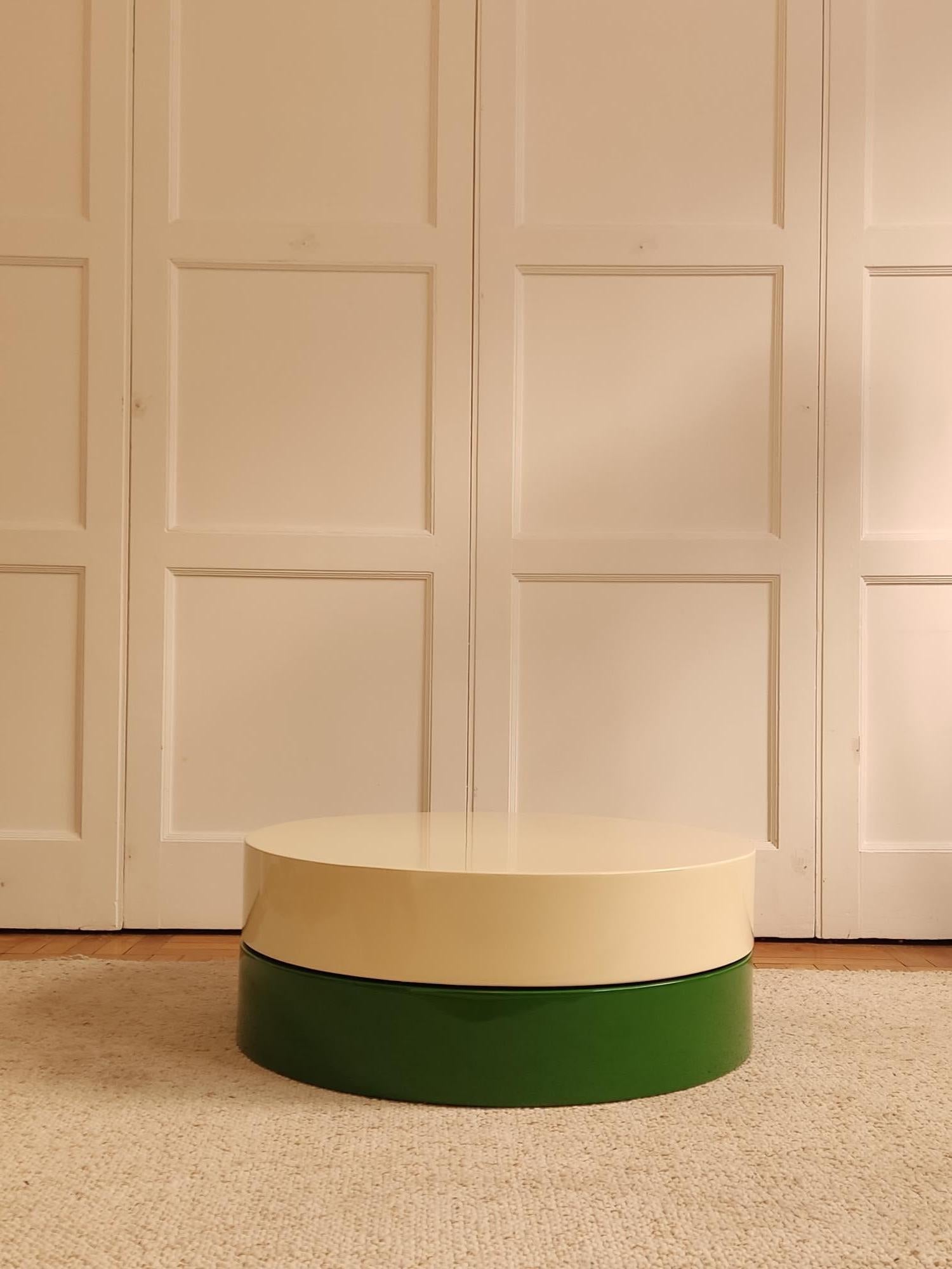 Circular lacquered wood table, French edition from the 1970s.

Two compartments, one of which is creamy white and rotates to reveal a green top with two storage bins.

Dimensions: H32 x D89 cm, table opening: W110 cm.