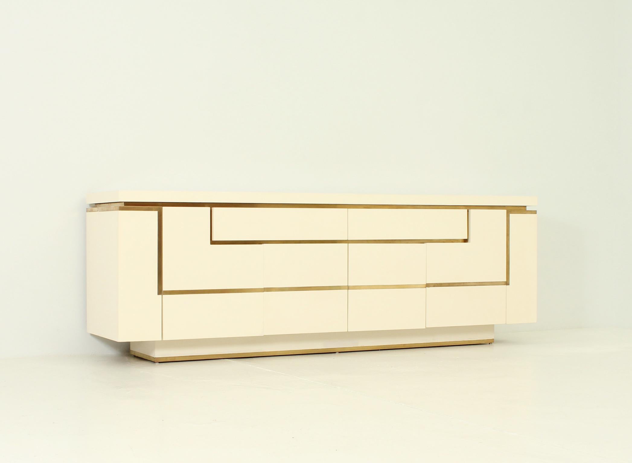 Large sideboard designed in 1970's by Jean-Claude Mahey, France. Cream lacquered wood and brass details. Two corner doors and four center doors with space for storage and two large drawers.