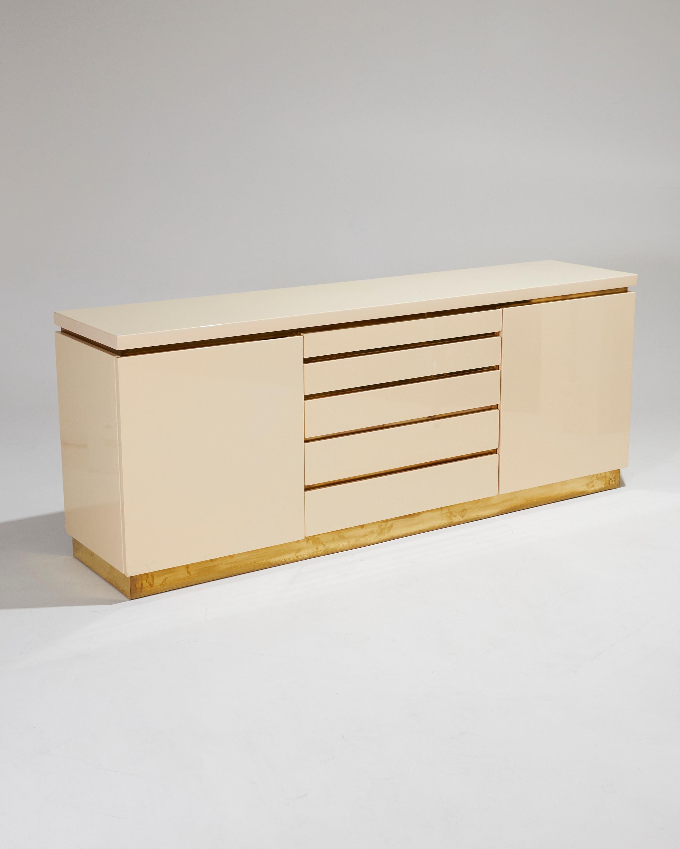 Credenza rettangolare in legno laccato beige con accenti in ottone, firmata dal designer francese Jean Claude Mahey negli anni Settanta. Il pezzo è composto da quattro cassetti centrali e due armadi laterali, tutti delineati da eleganti finiture in