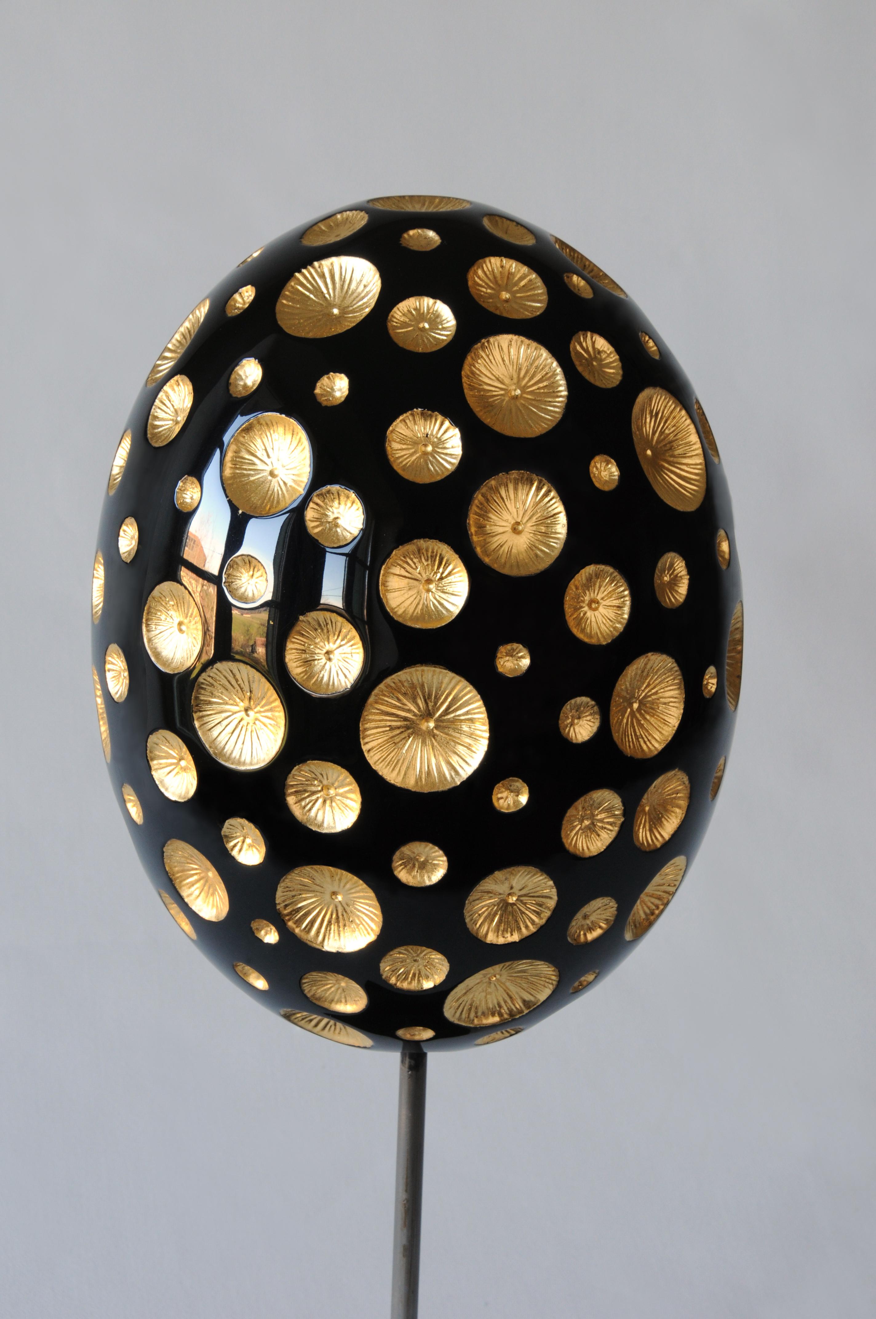 Egg-shaped sculpture of lacquered walnut and gold leaf. Carefully sculpted round craters of gold provide a striking contrast to the sleek black wood of the egg. Influenced by early 20th century masters such as Majorelle, Gallé, the artist takes the