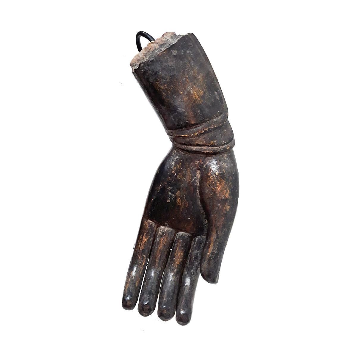 A wooden sculpture of a Buddha hand in a traditional gesture known as
Verada Mudra, meaning Compassion / Sincerity, early 20th century.

Once part of a large Buddha sculpture, this fragment was reclaimed and mounted on a black metal stand as a